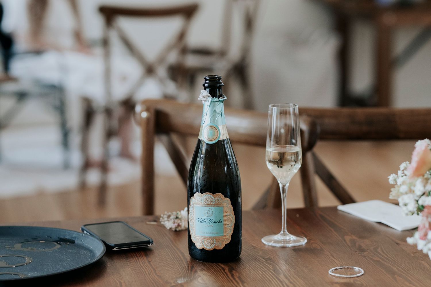 Champagne bottle and wine glass on wooden table at wedding reception.