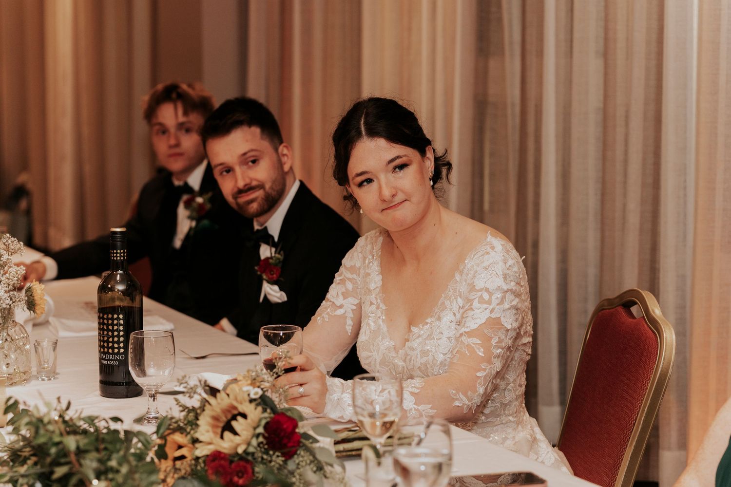 Wedding reception dinner scene with elegant table settings and floral centerpieces.