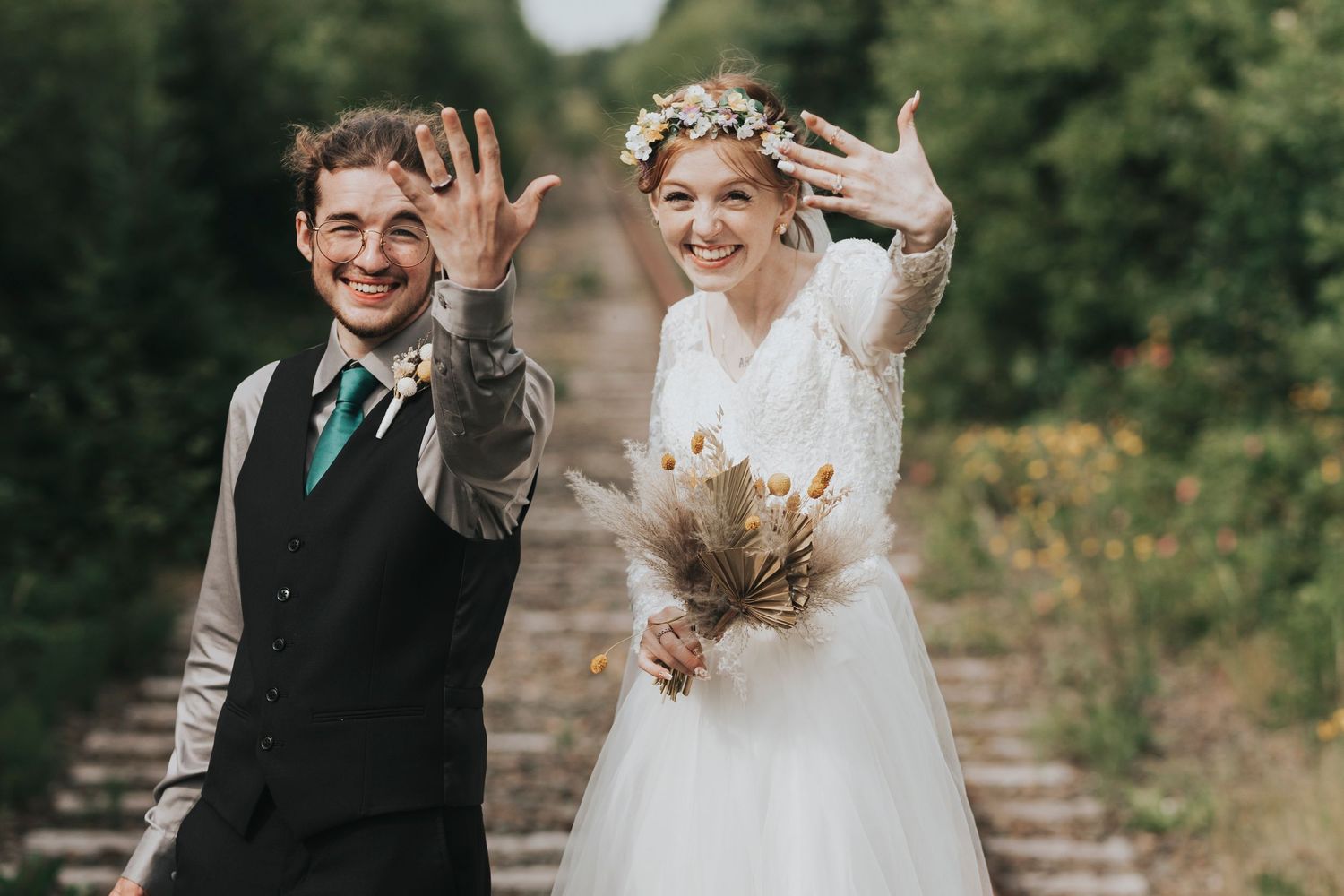 A happy couple in wedding attire show off their wedding rings.