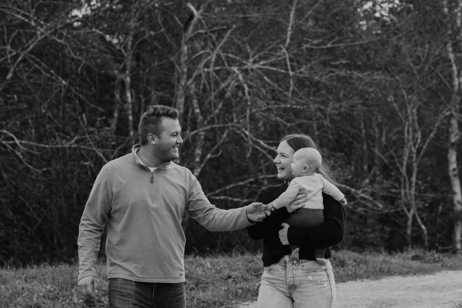 Black and white photo of parents playing with baby outdoors.