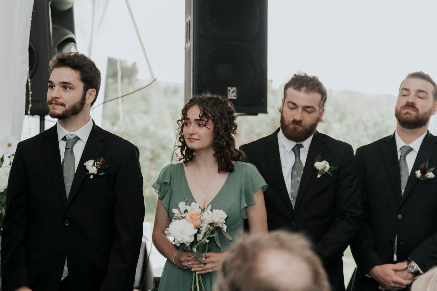 Wedding party members standing at attention during outdoor ceremony.