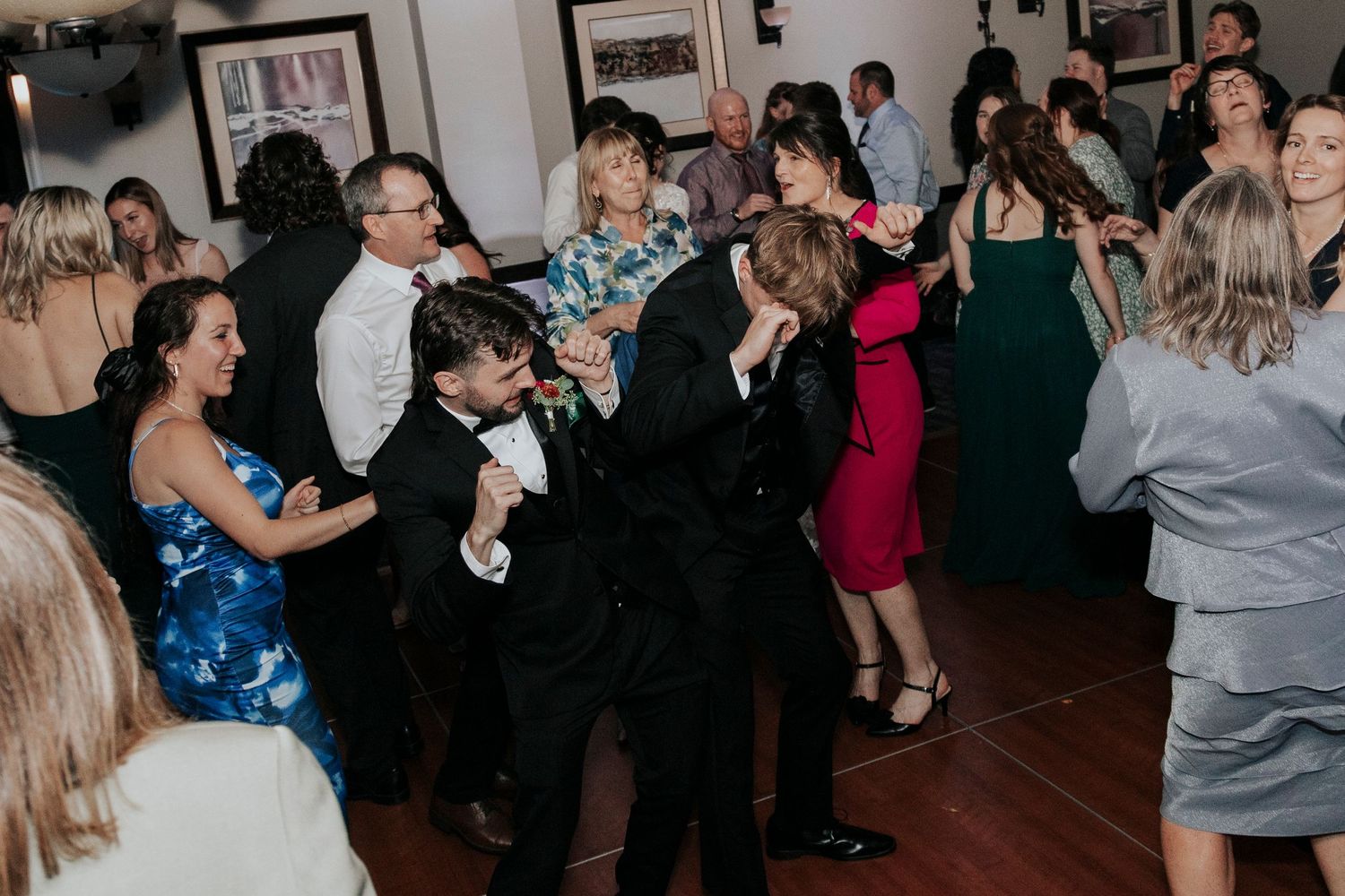 Wedding guests dancing and celebrating on the reception dance floor.