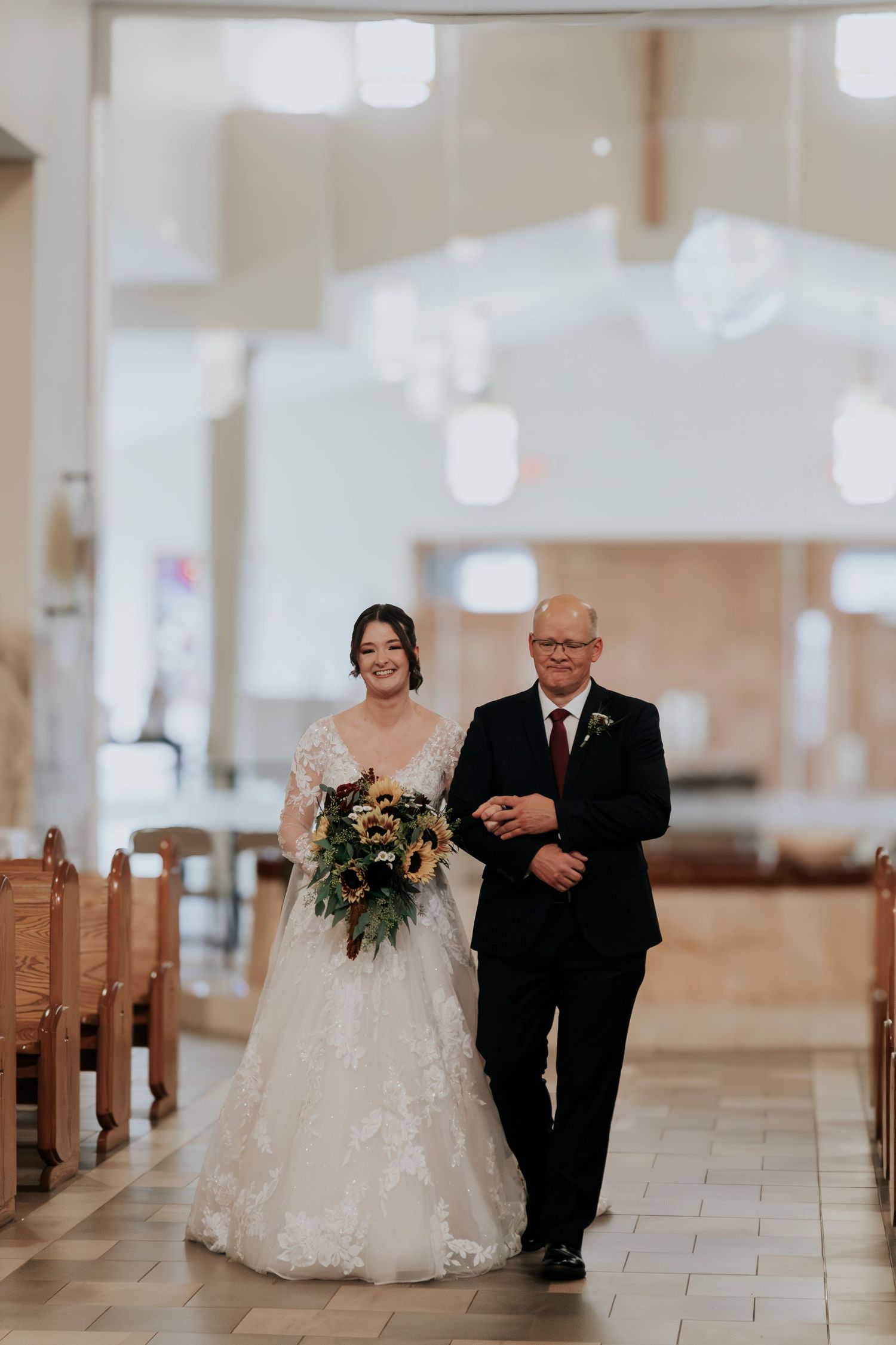 Bride walks down church aisle with her father during a beautiful wedding ceremony.