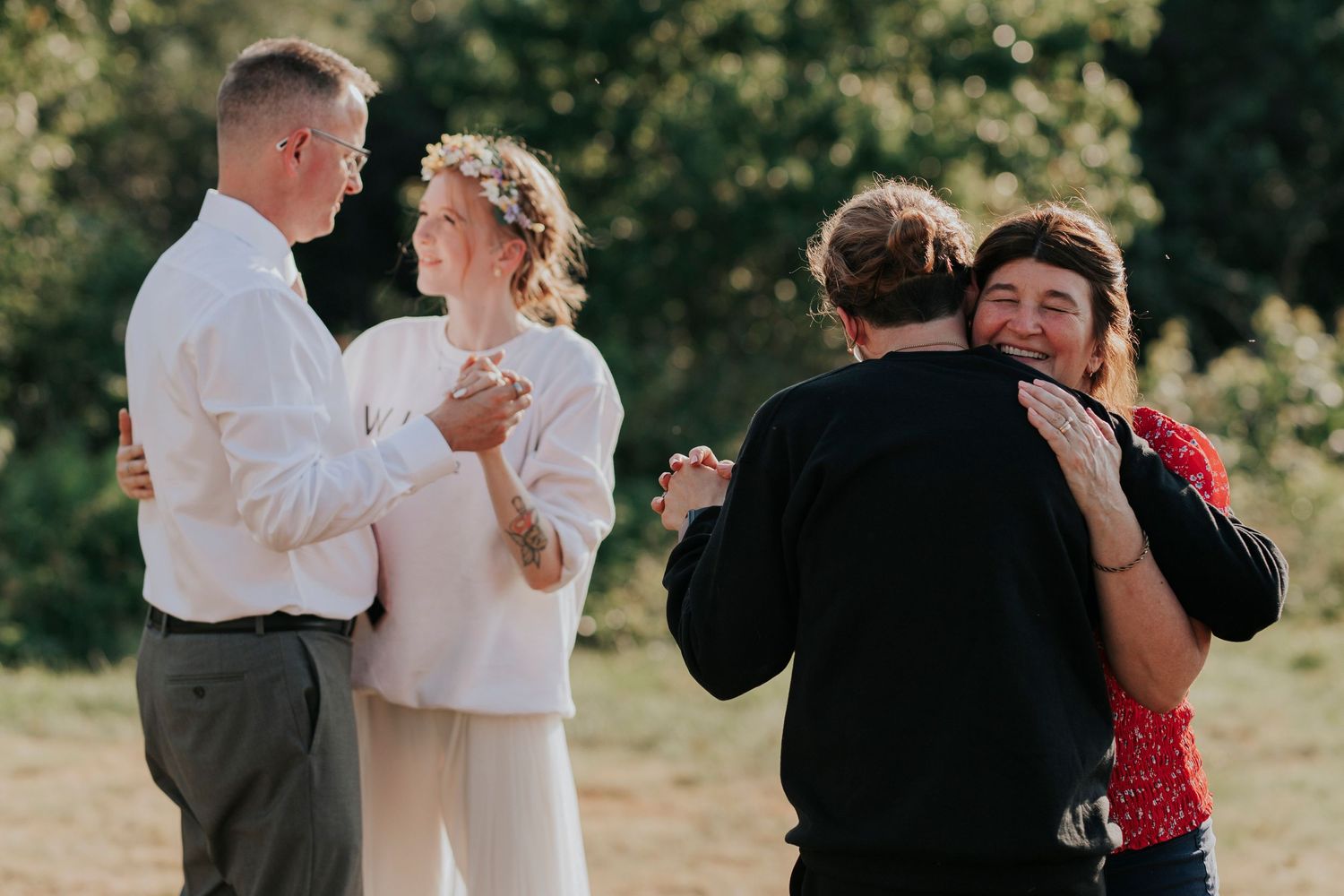 The bride dances with her father and the groom dances with his mother during the reception of a summer wedding.