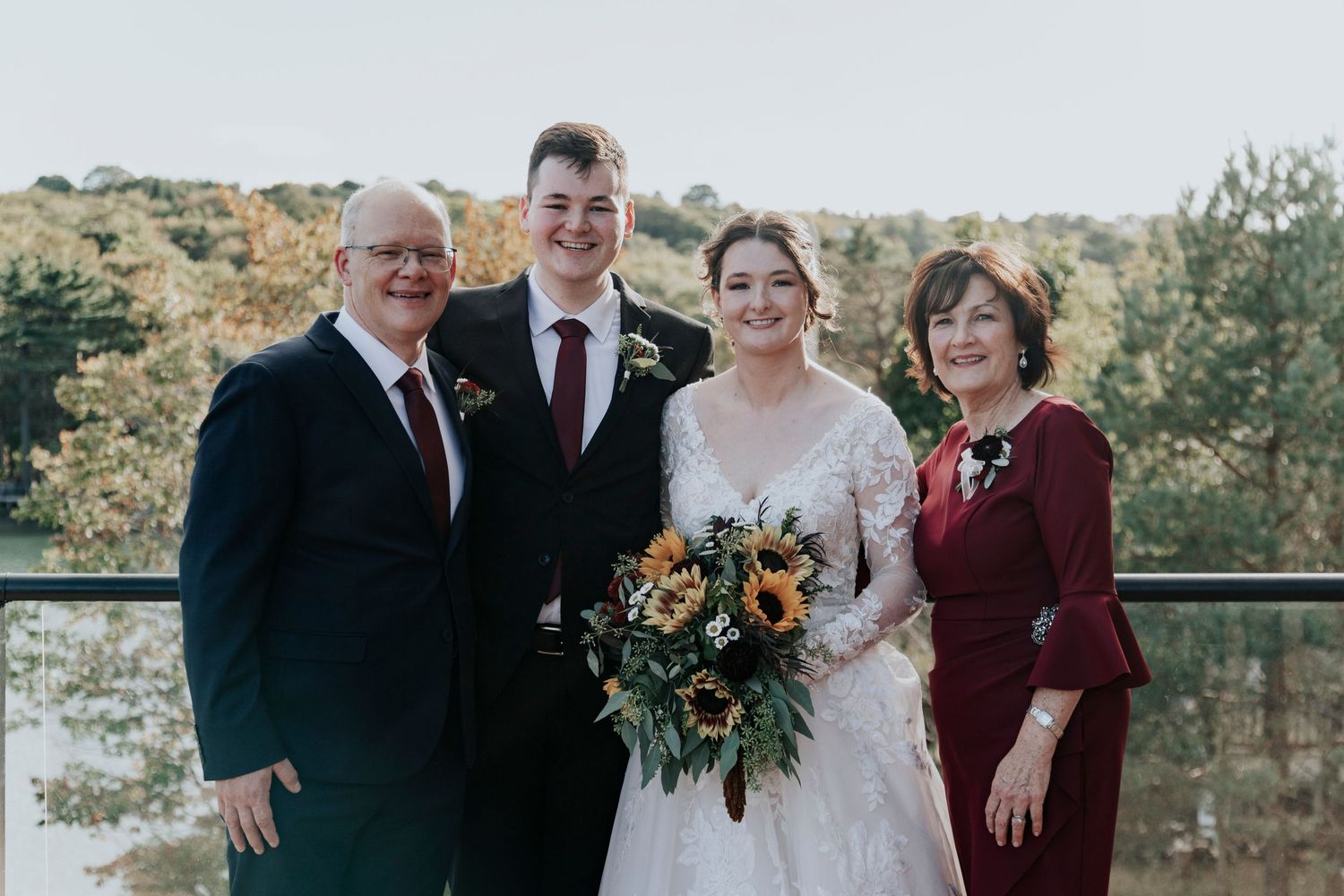 Wedding party group photo on a balcony with scenic autumn backdrop.