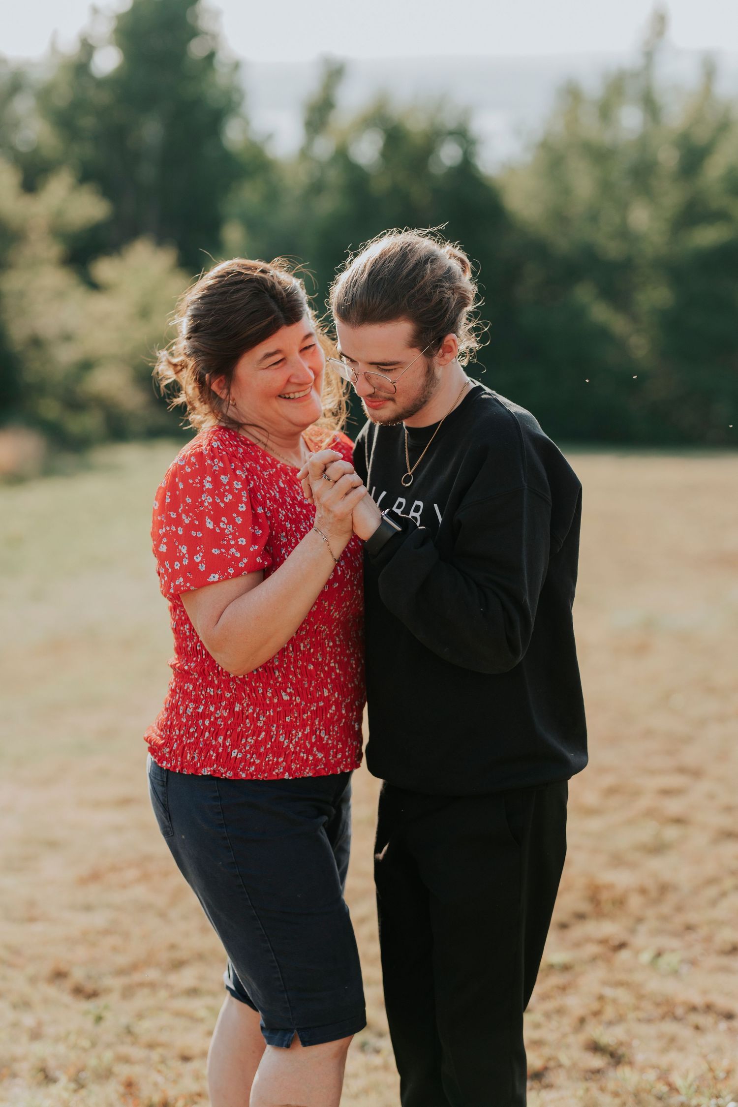 A mother and son shares a joyful moment together outdoors on a sunny day.