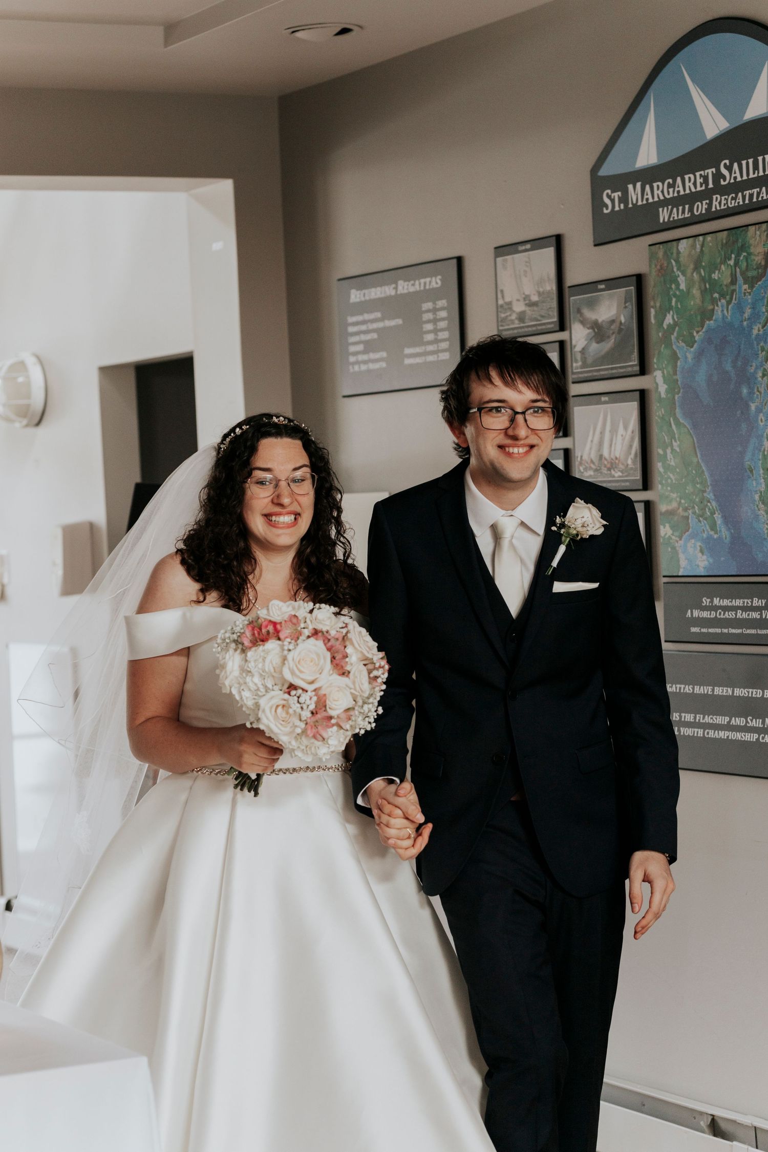 A wedding couple stands indoors near an ocean-themed display.