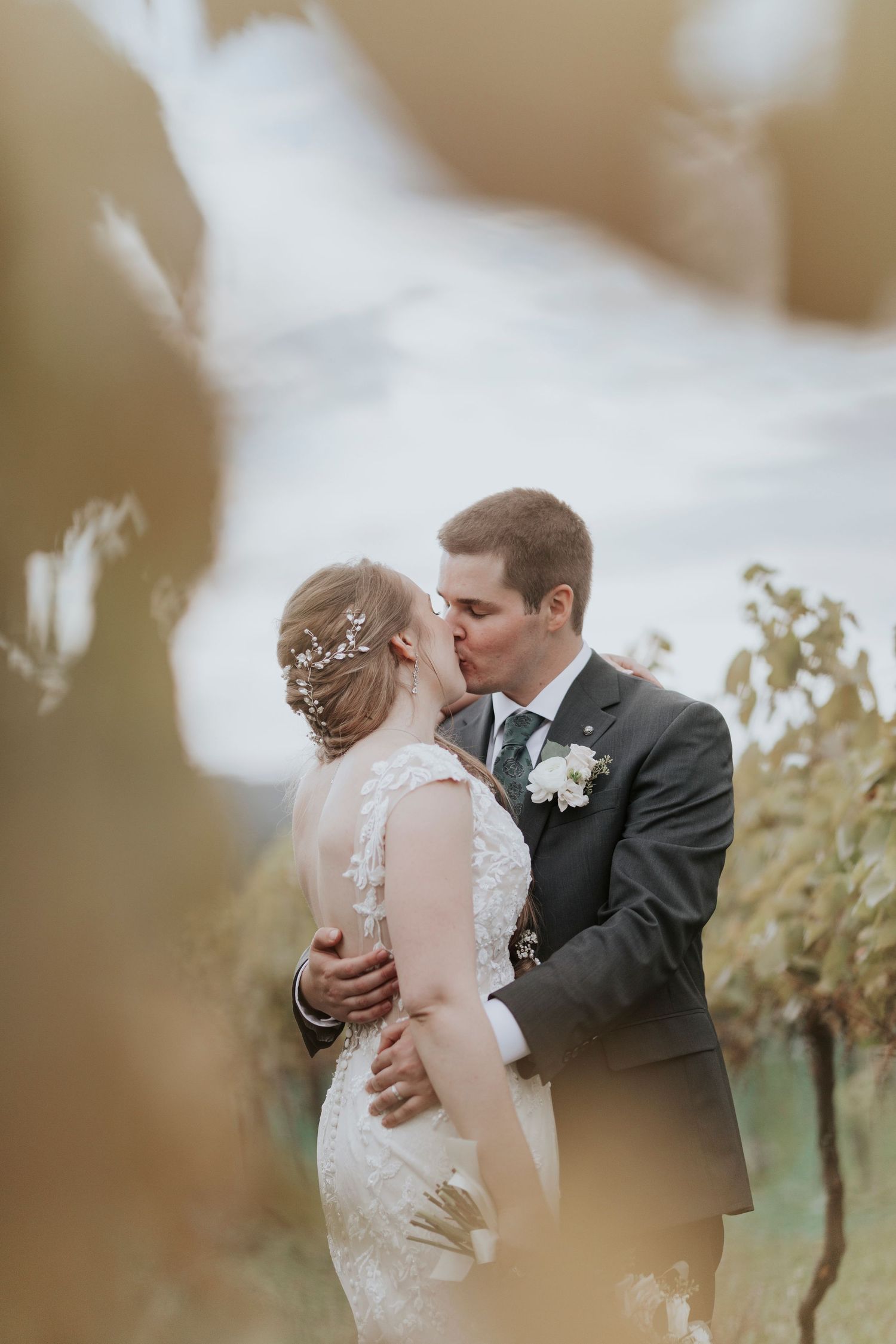 Intimate wedding moment captured between couple in vineyard with soft lighting.