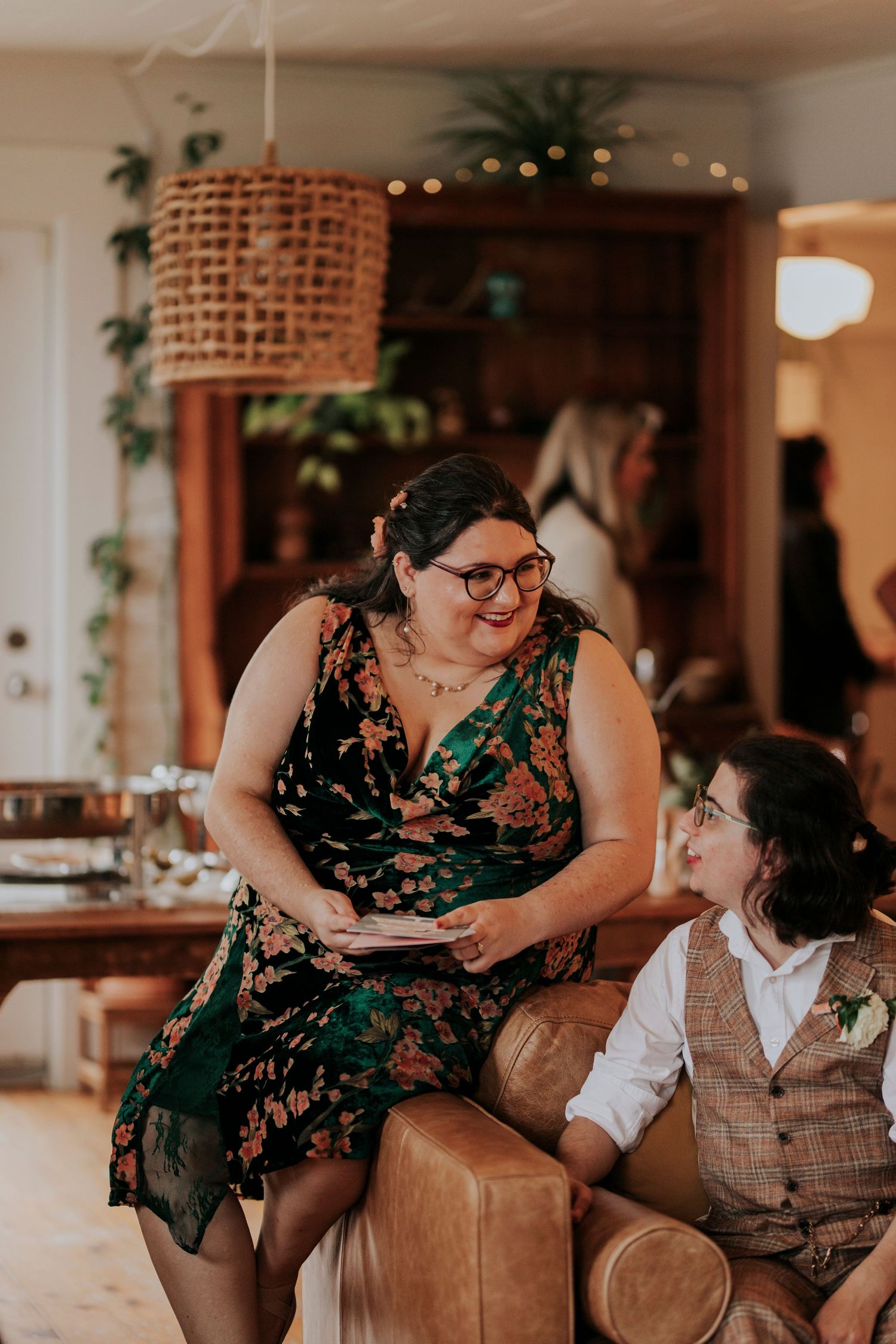Two people sharing a moment on a leather couch under a woven pendant light.