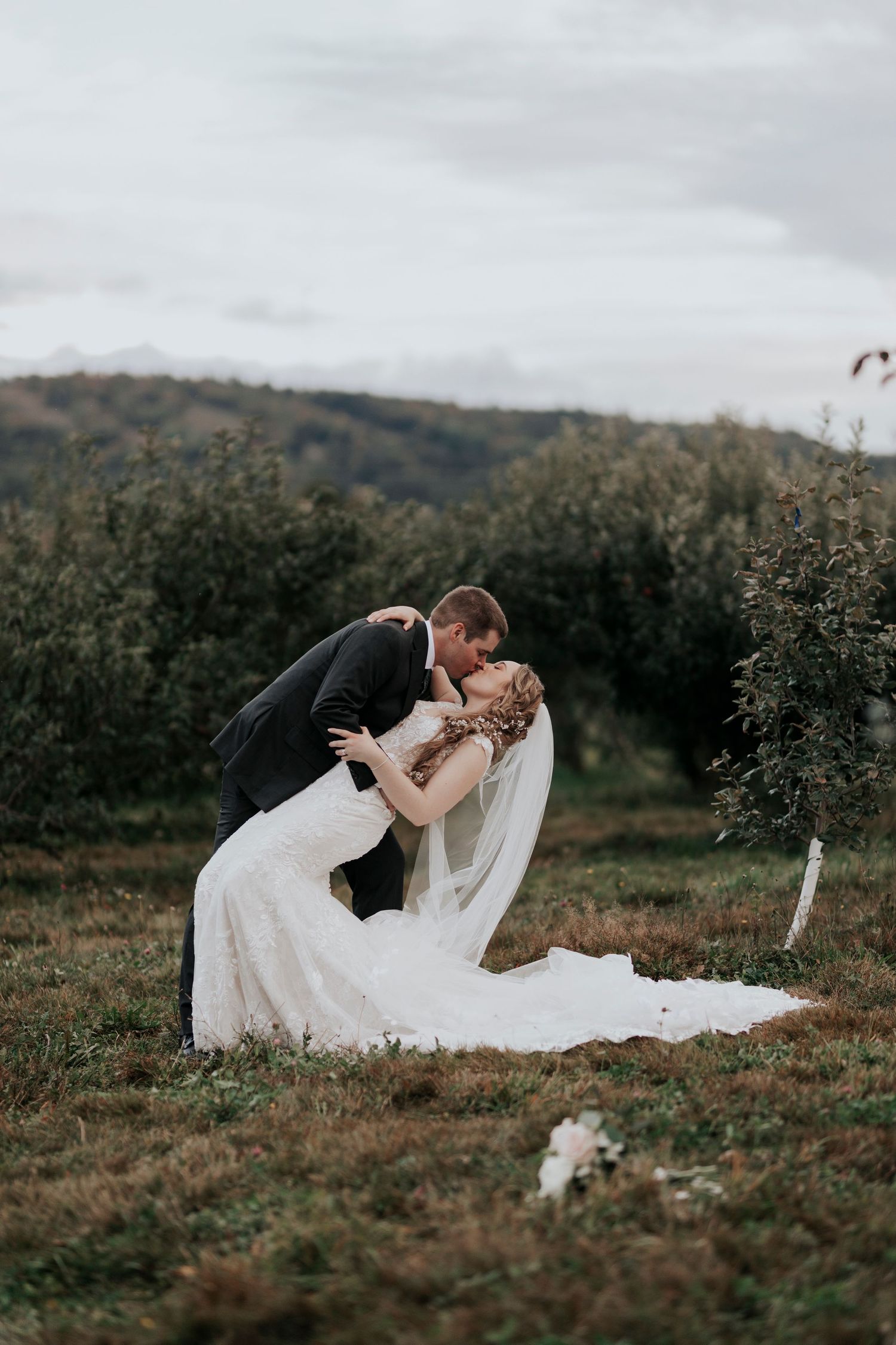 Dramatic wedding dip pose surrounded by hillside autumn scenery.