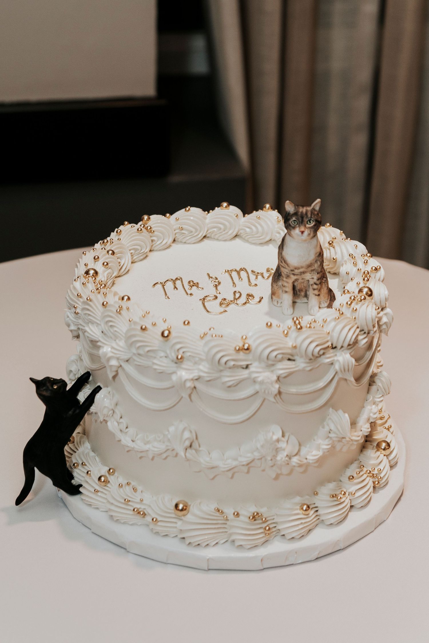 White wedding cake decorated with black and gray cat silhouette toppers.