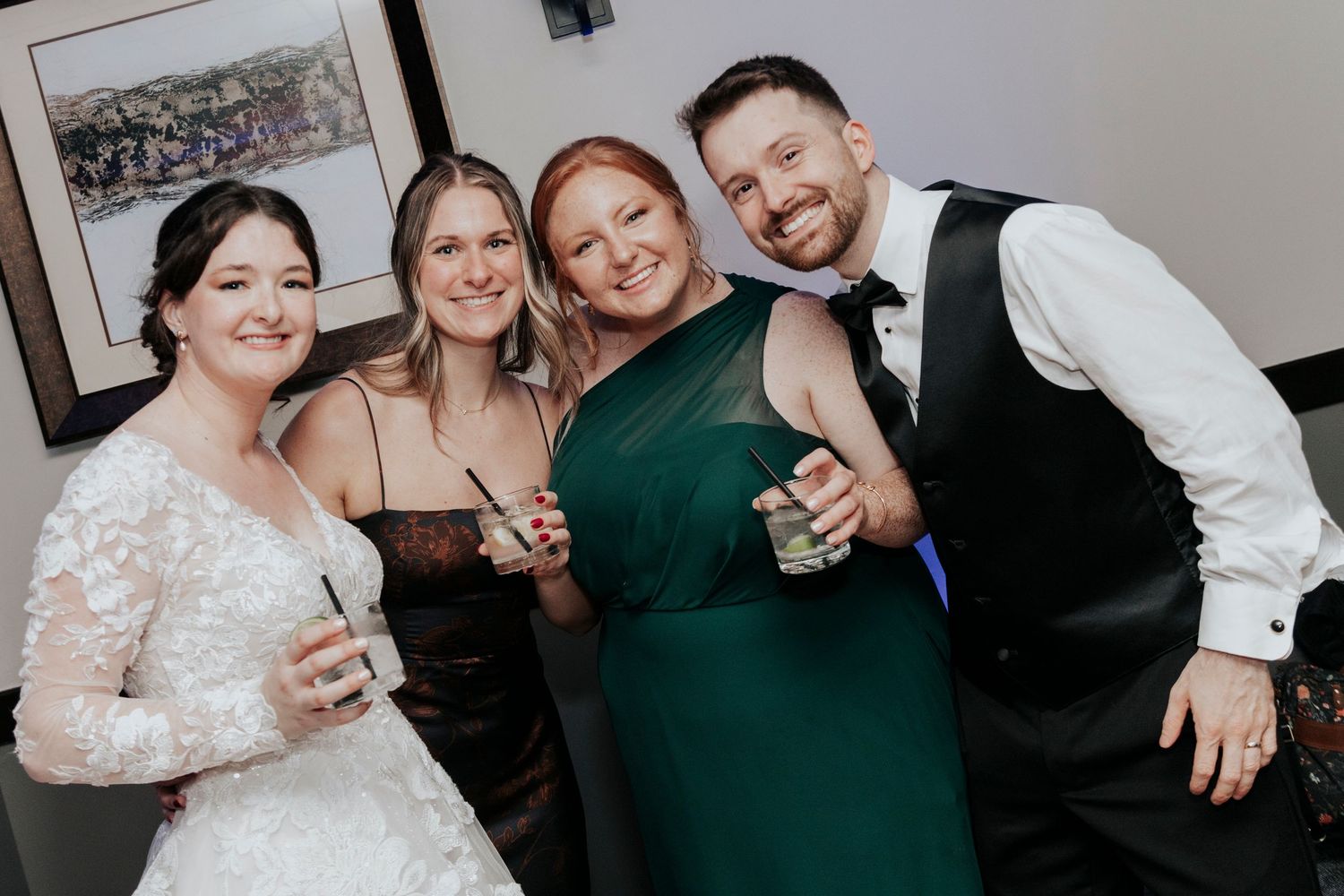 Wedding party poses together for a celebratory photo with drinks.