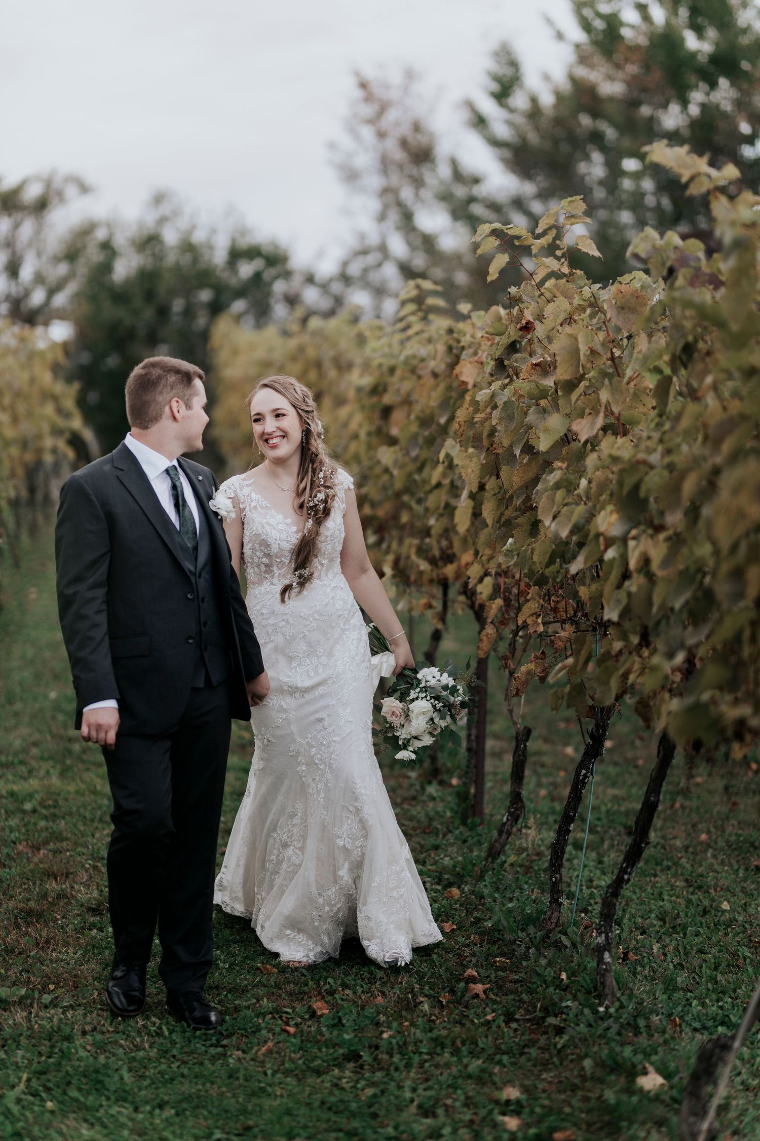 Newlyweds share romantic moment among vineyard rows during fall wedding.