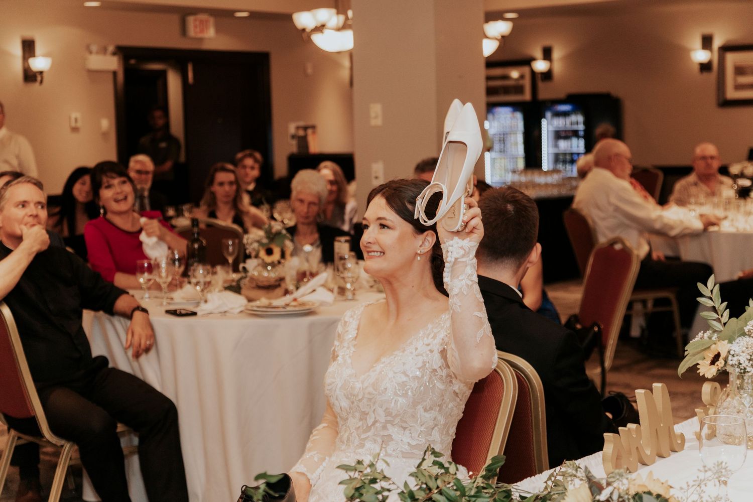 Wedding reception guests celebrate during dinner in an elegantly decorated banquet room.