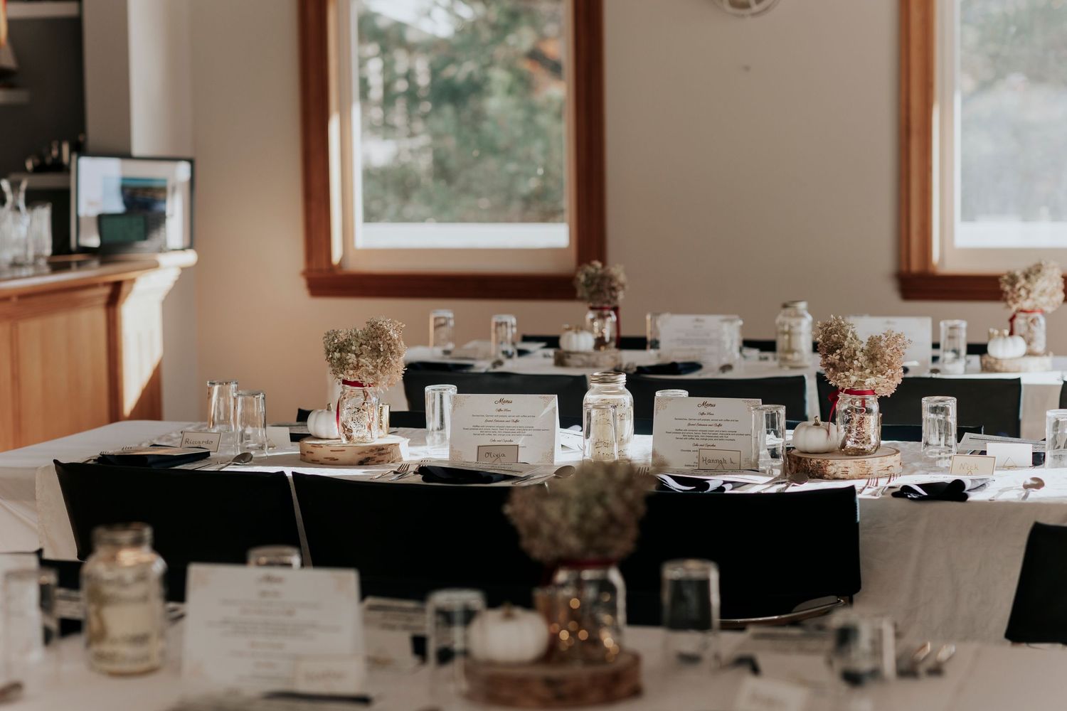 Elegant wedding reception tables with black linens and place cards set for a formal dining event.