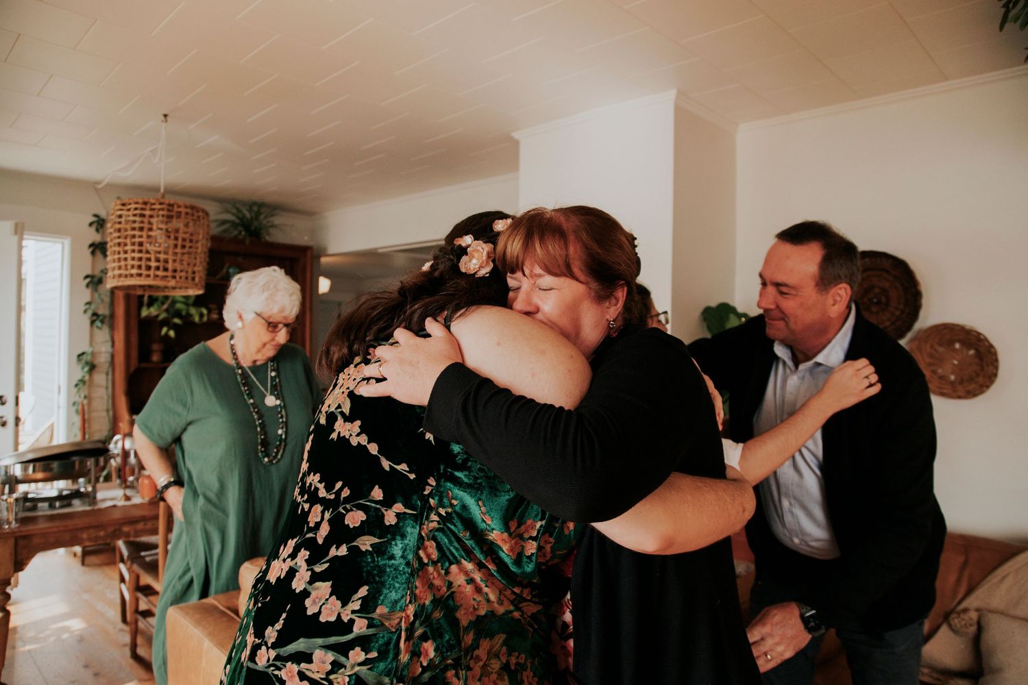 A group embraces in an emotional moment during a gathering in a cozy living room interior.