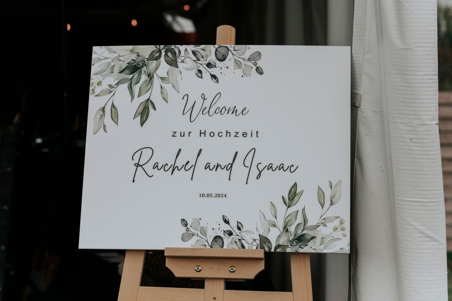 Elegant wedding welcome sign with greenery design on wooden easel.