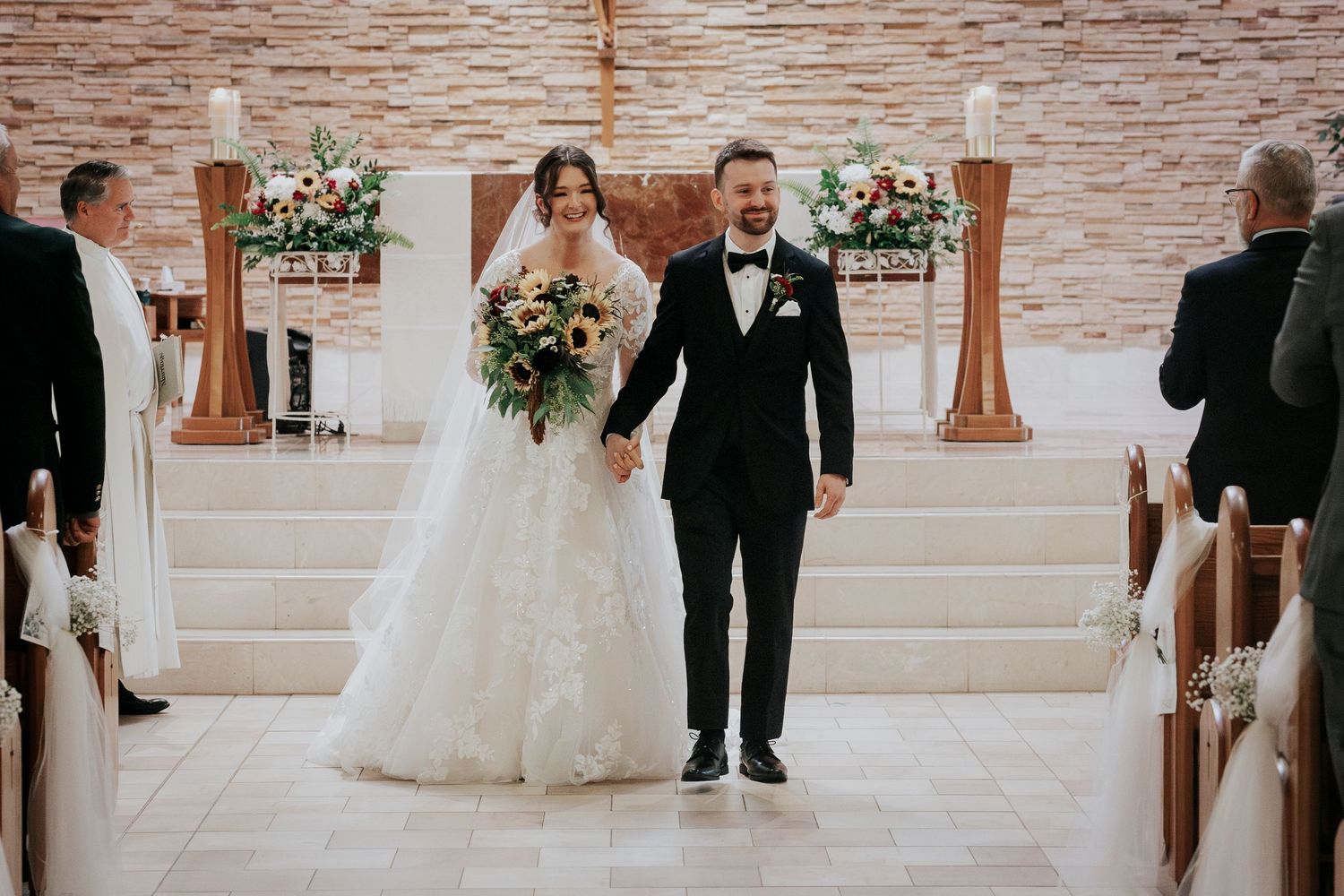 Newlyweds walking down church aisle after ceremony.