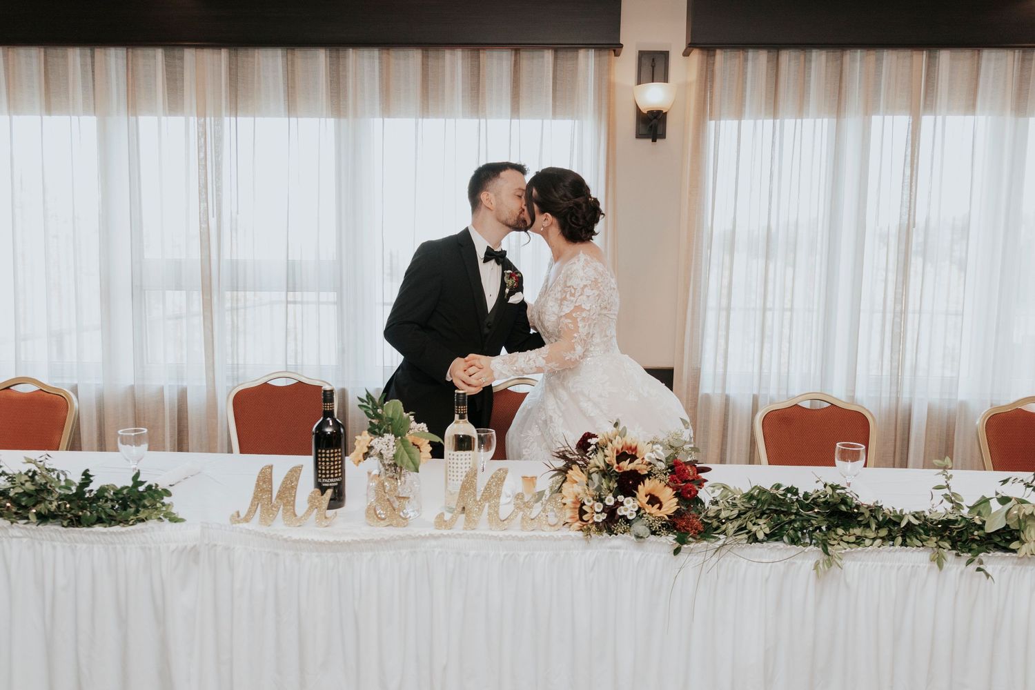 Bride and groom share an intimate moment at their decorated head table during the reception.