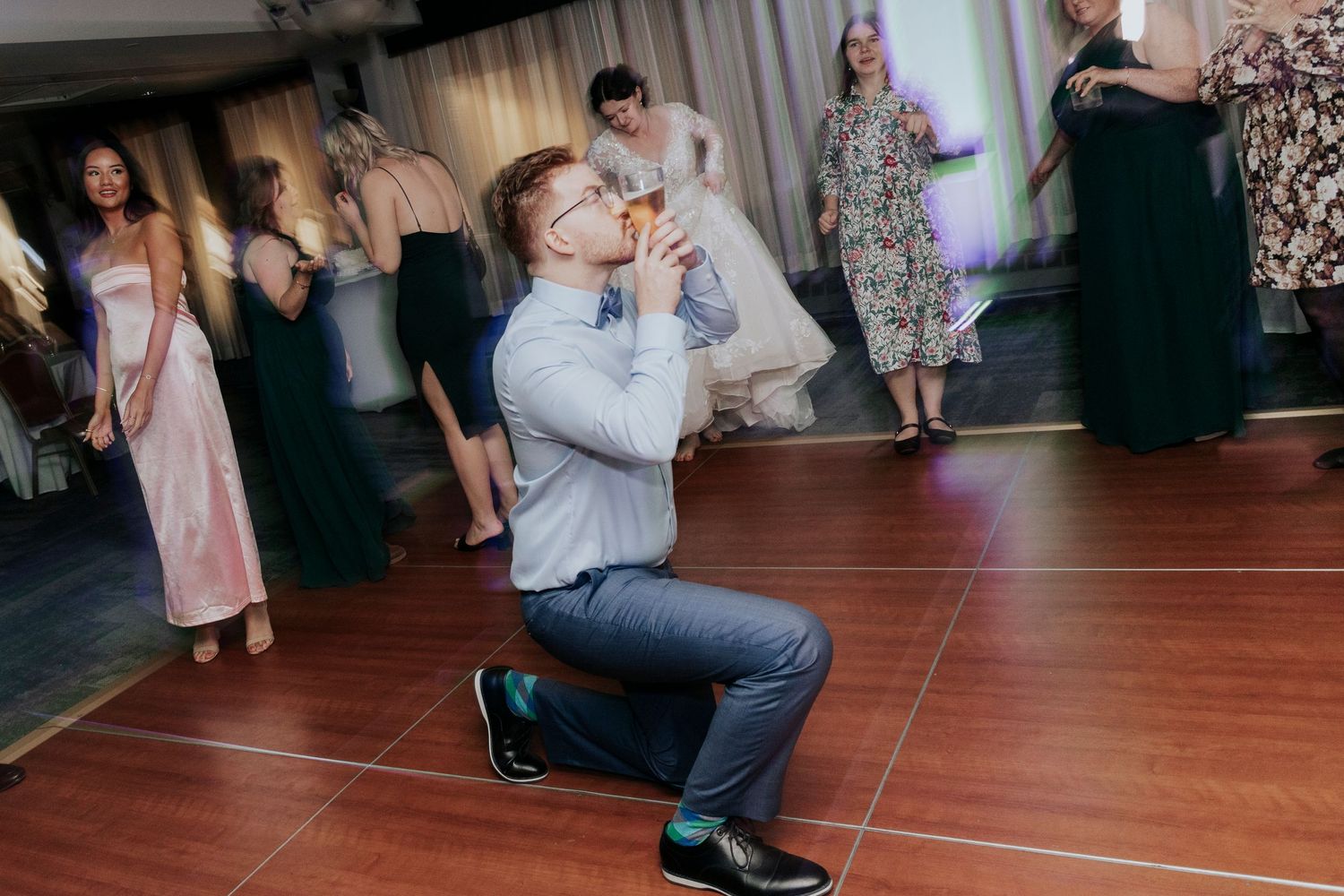Wedding guest takes photos while kneeling on the dance floor.