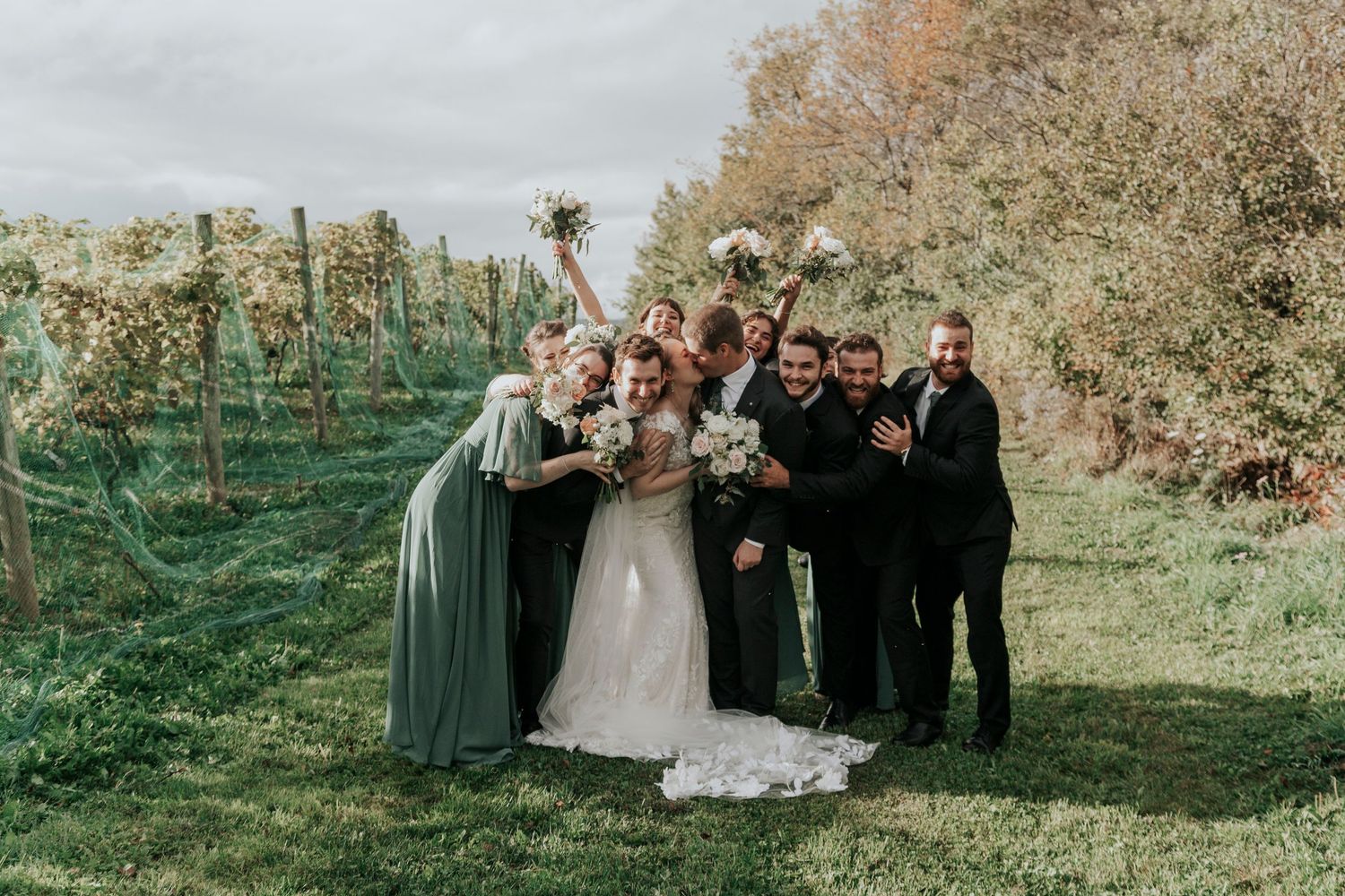 Wedding party celebrating with raised arms in front of autumn foliage.