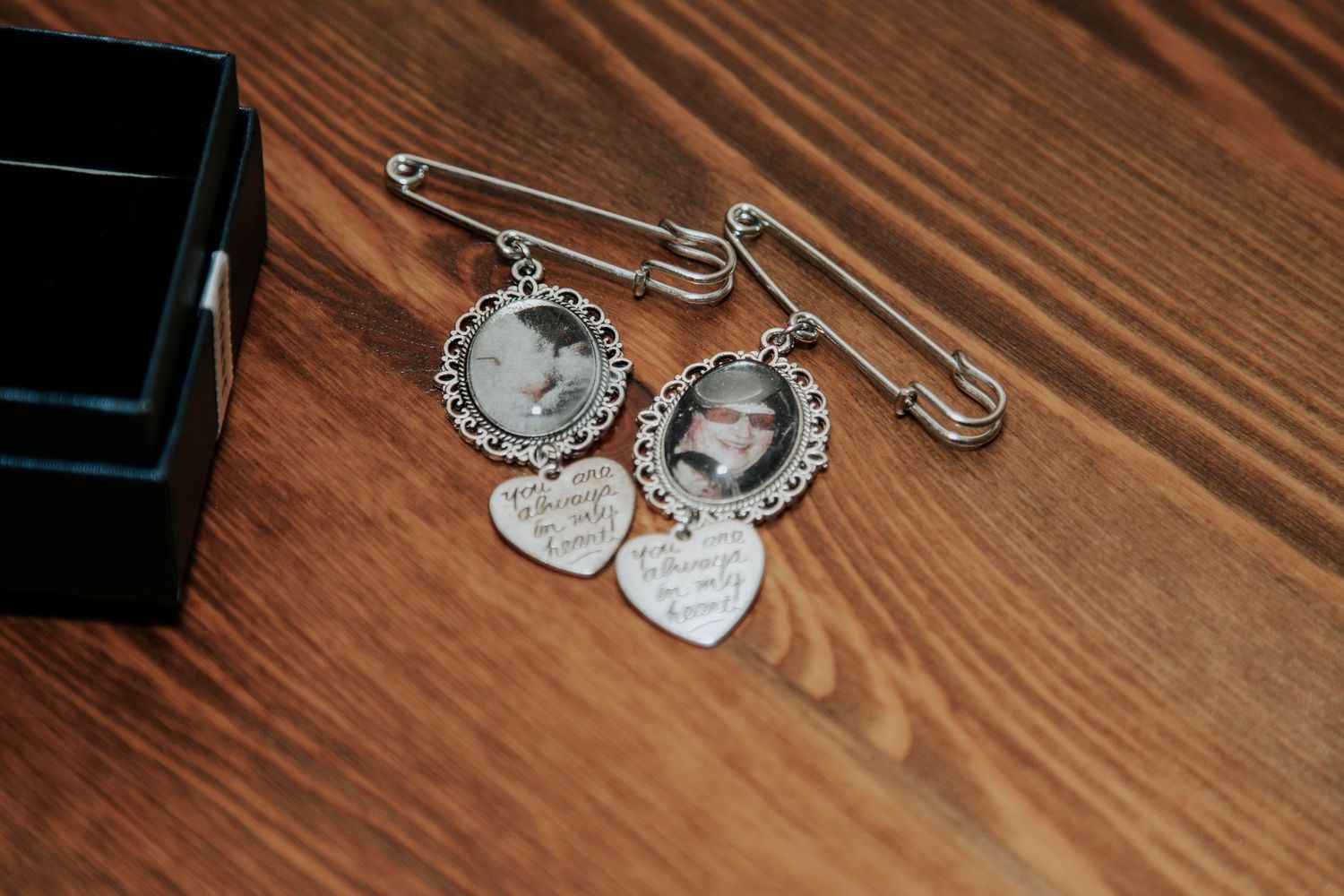 Wedding jewelry and accessories laid out on wooden surface including delicate pins and charms.