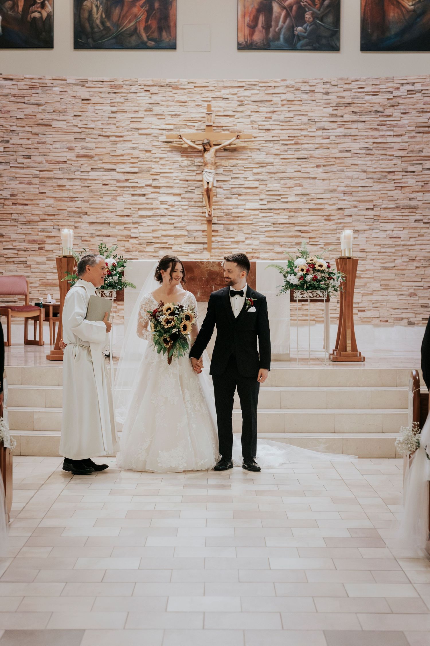Traditional wedding ceremony with priest at altar and floral arrangements.