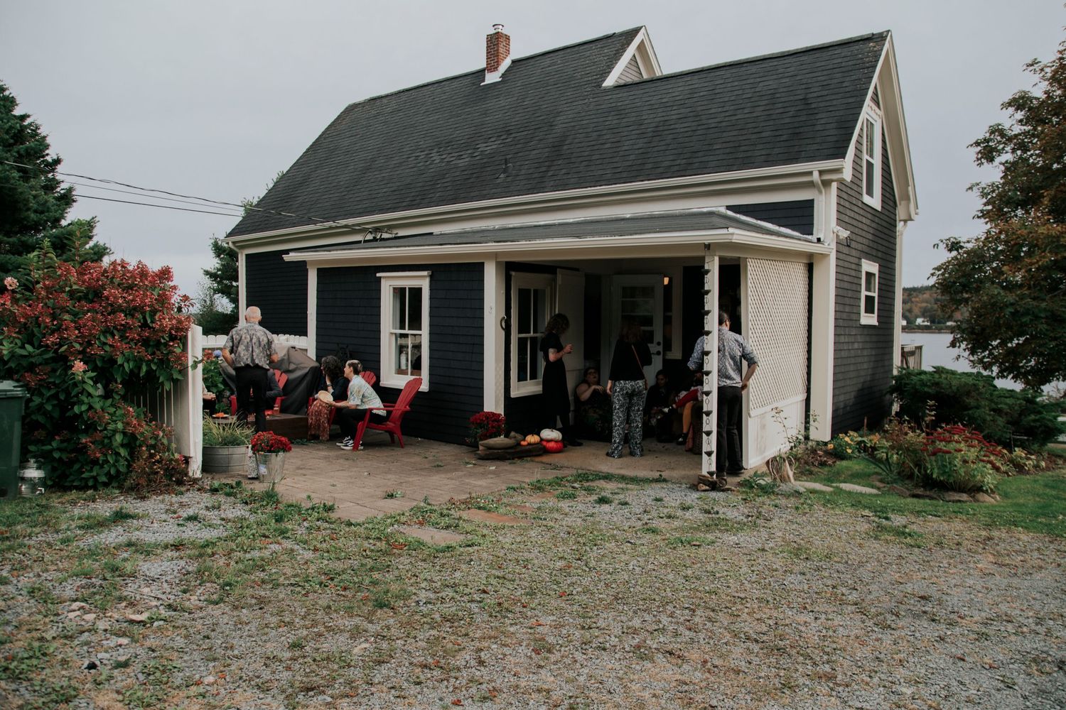 Gray farmhouse with white trim and front porch surrounded by garden landscaping.