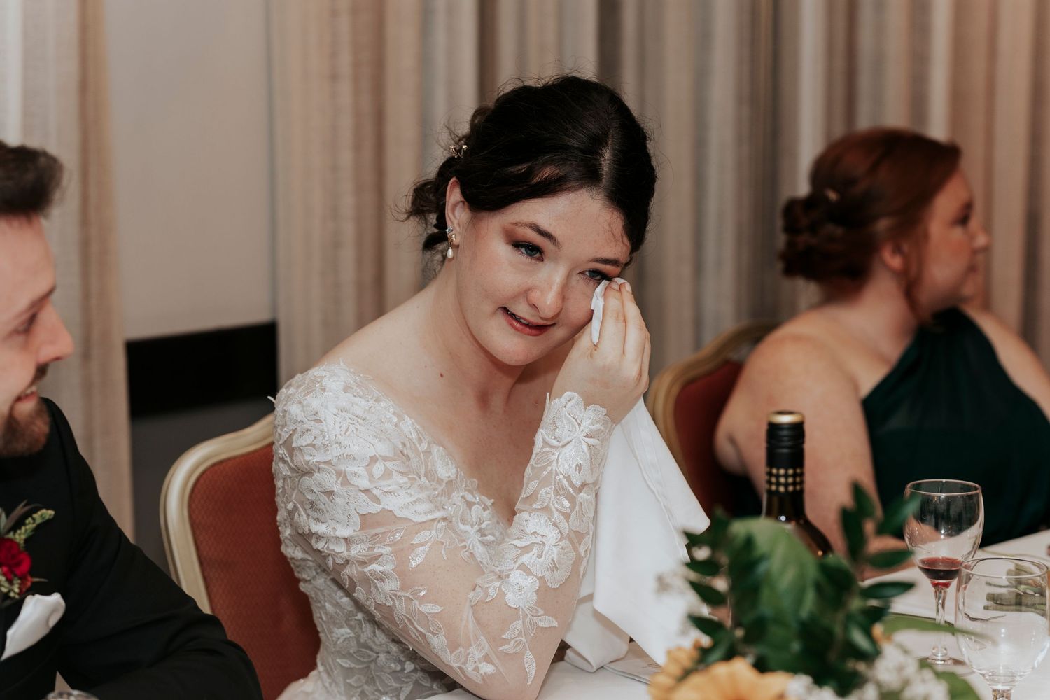 Emotional moment captured during wedding reception dinner with elegant table decor.