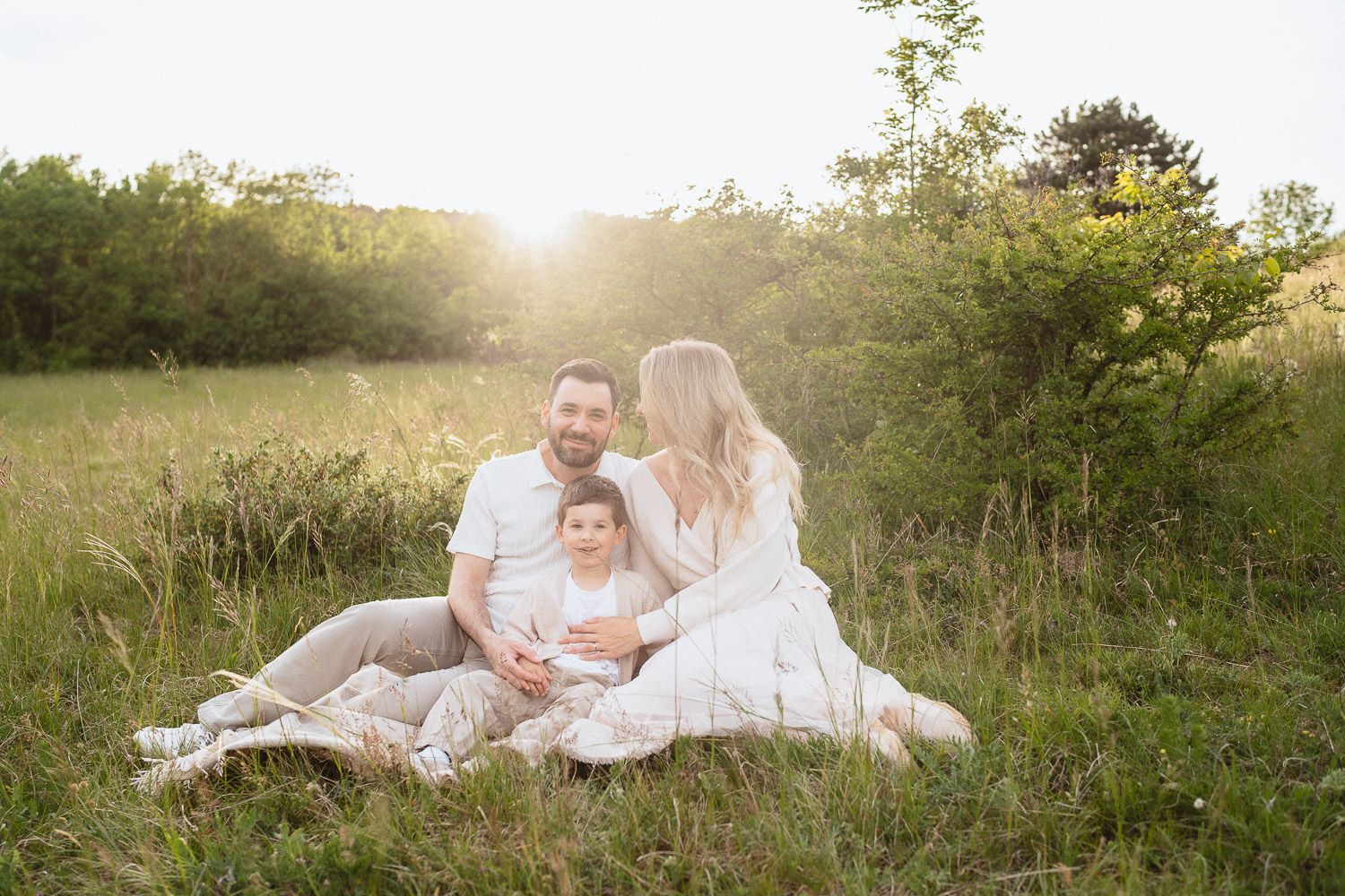 Familie sitzt gemeinsam auf einer Decke in der Natur.