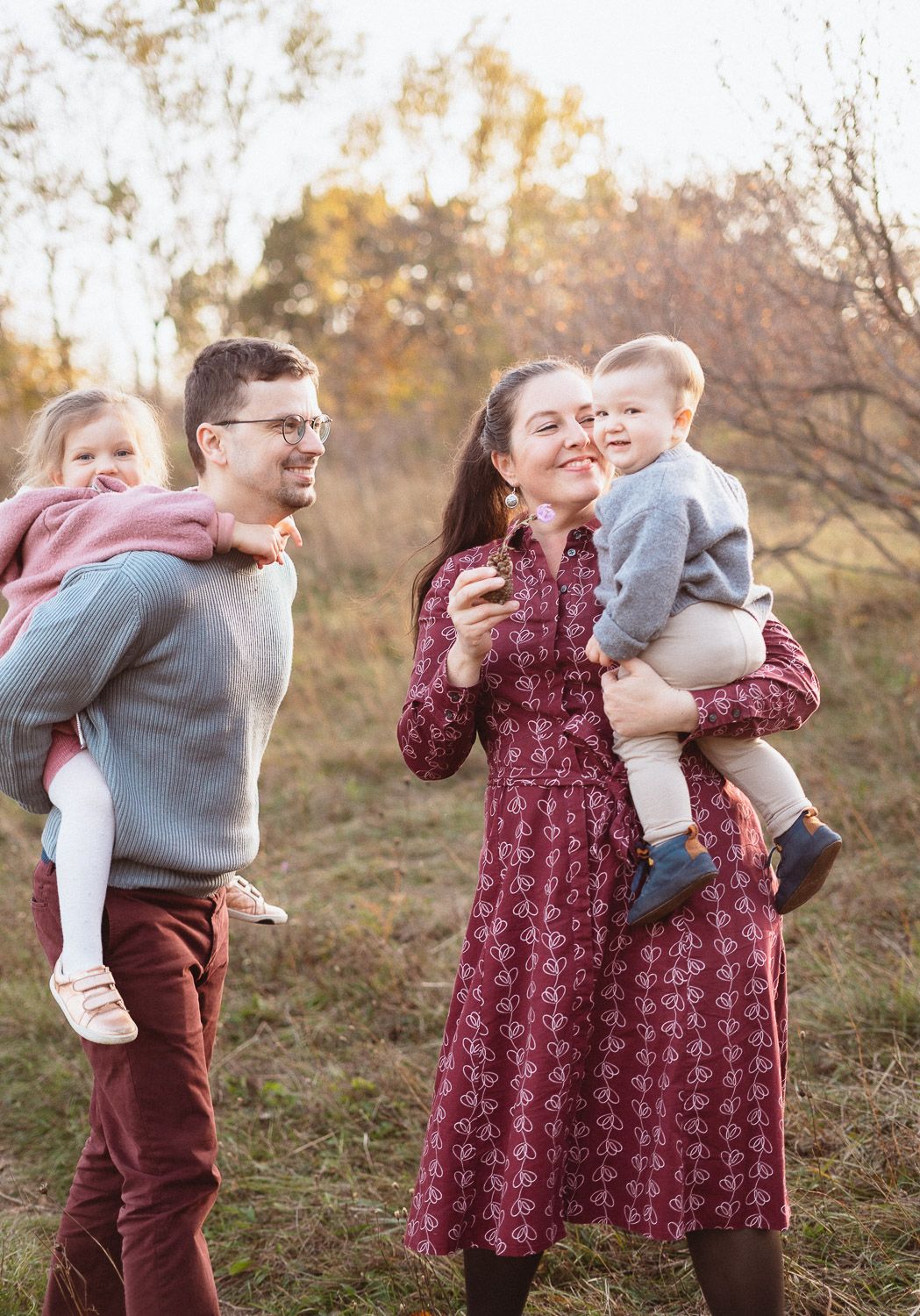 Vater trägt seine Tochter auf den Schultern, während die Mutter ihren Sohn im Arm hält