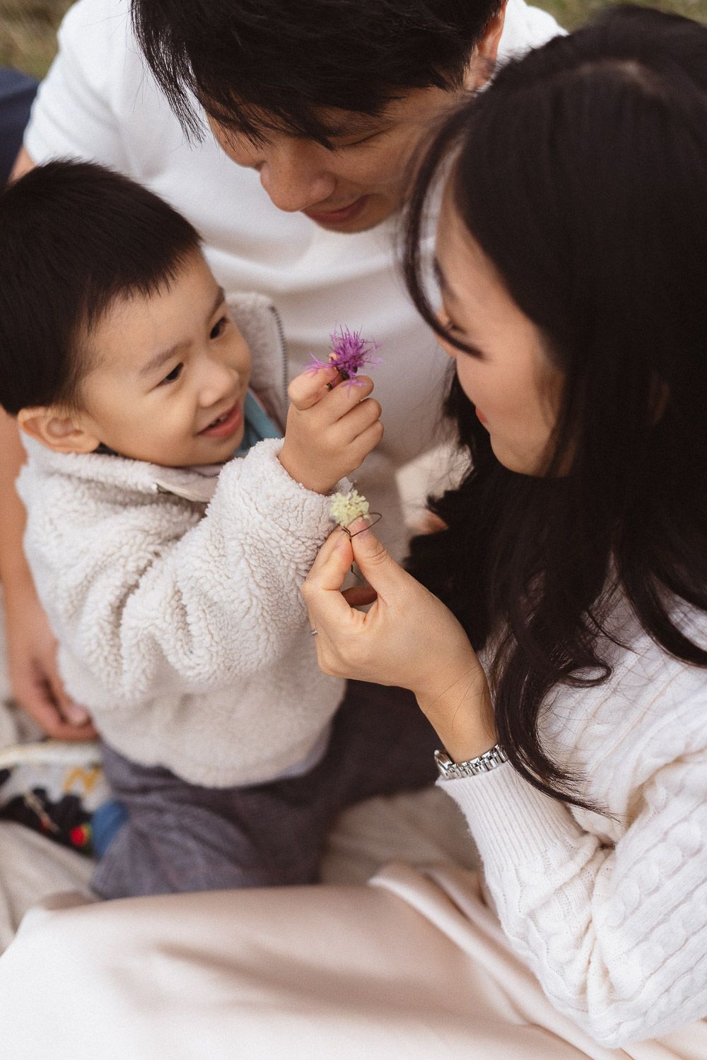 Nahaufnahme einer Familie, der Sohn zeigt seiner Mutter eine Blume.