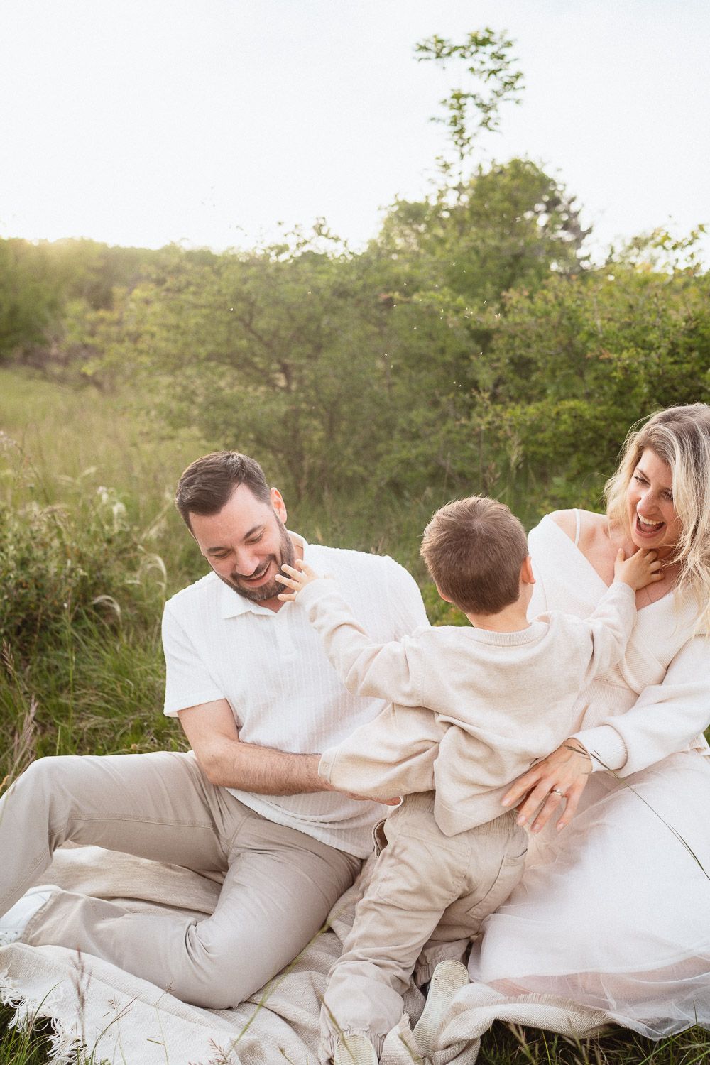 Eltern spielen mit ihrem Sohn und kitzeln ihn während eines fröhlichen Familienmoments