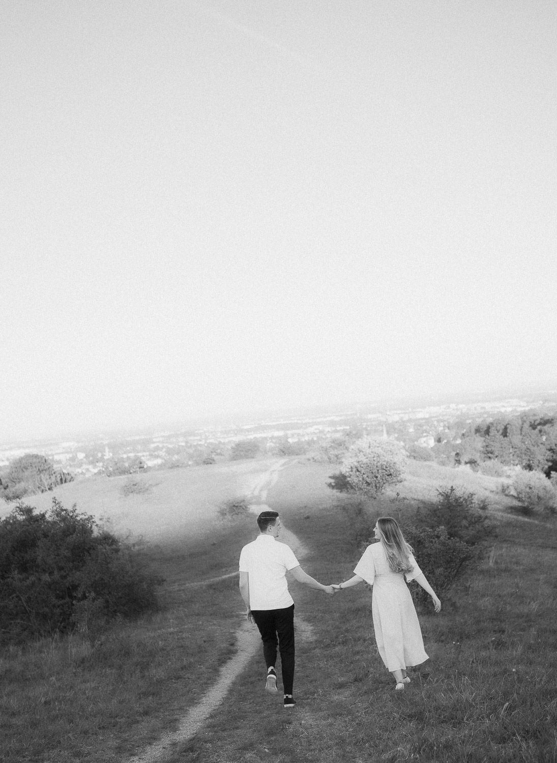 Paar läuft Hand in Hand und blickt sich an, mit Blick auf Perchtoldsdorf im Hintergrund.