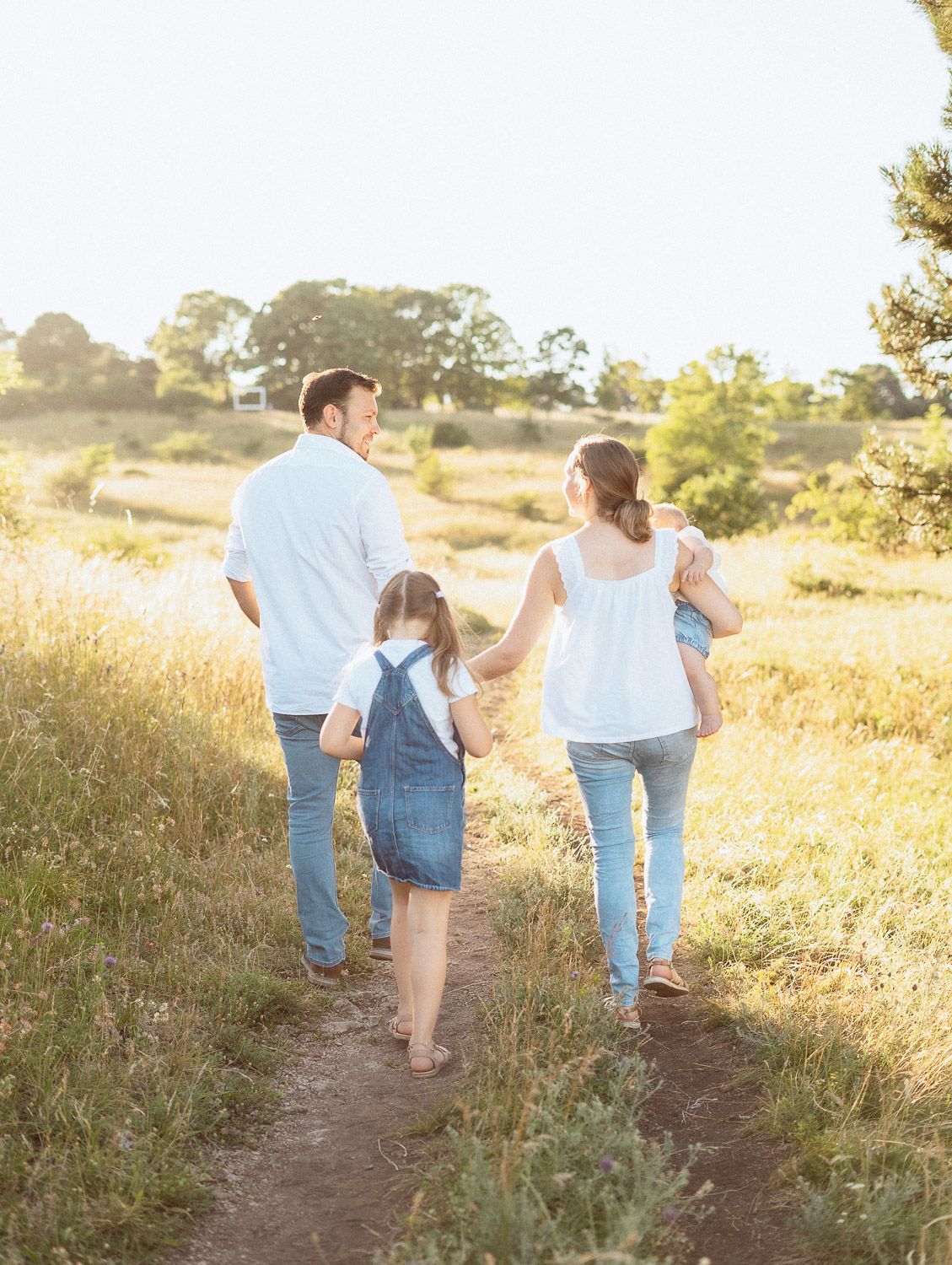 Familie mit zwei Kindern geht gemeinsam durch die Natur, während die Eltern sich ansehen
