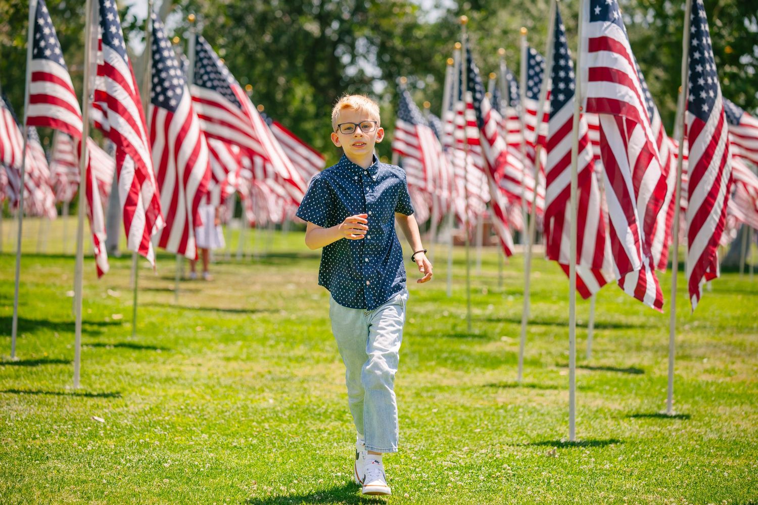 Young boy running in field of American flags