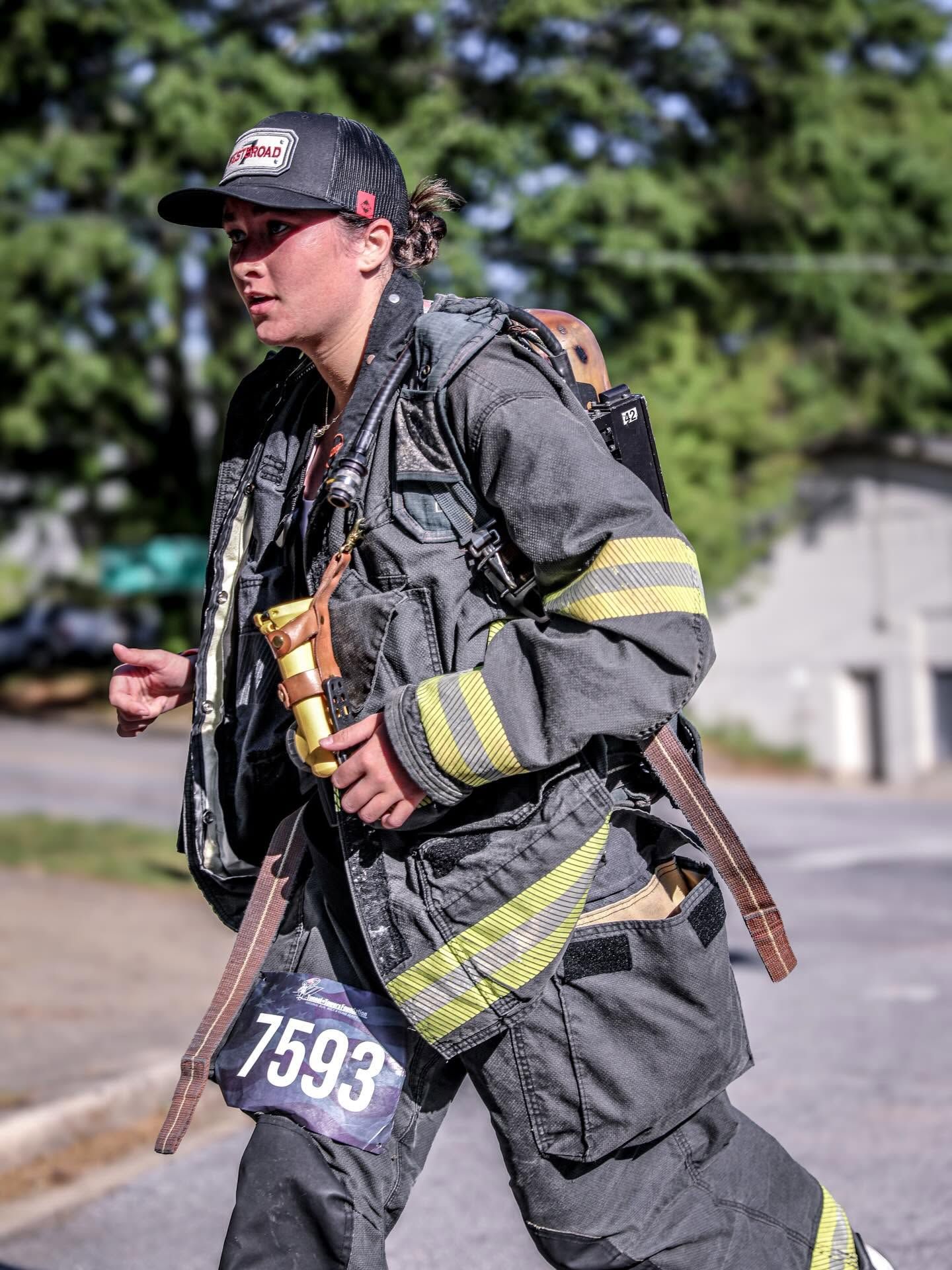 Firefighter in full gear with race number 7593 running during a firefighter competition event.