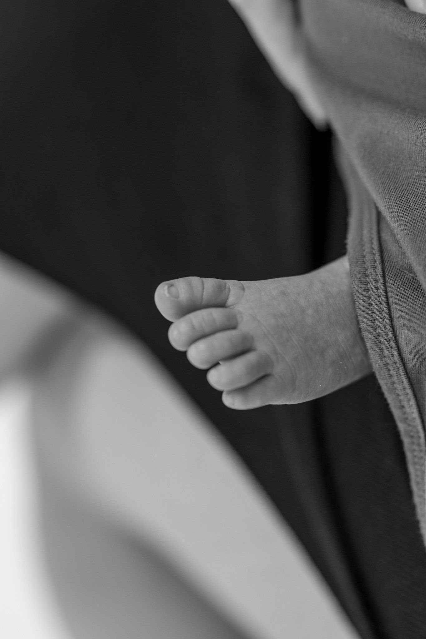 Close-up black and white photo of tiny newborn baby foot and toes.