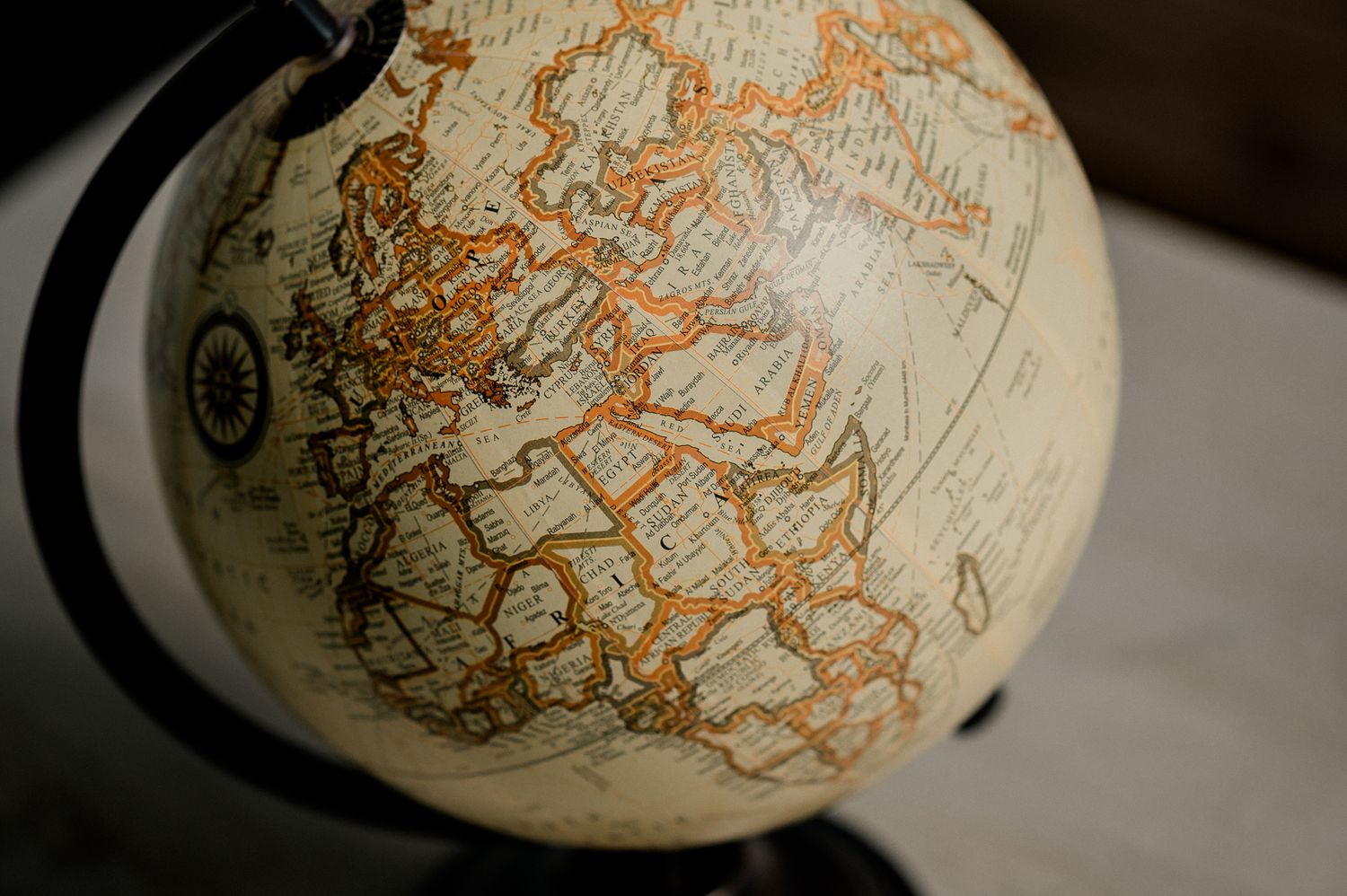 Antique world globe with orange-outlined countries displayed on a dark metal stand.