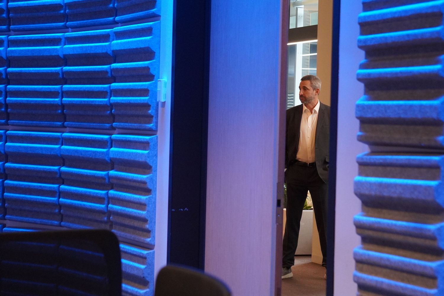 Candid corporate photography of a speaker in a suit waiting backstage to present at a large business event.