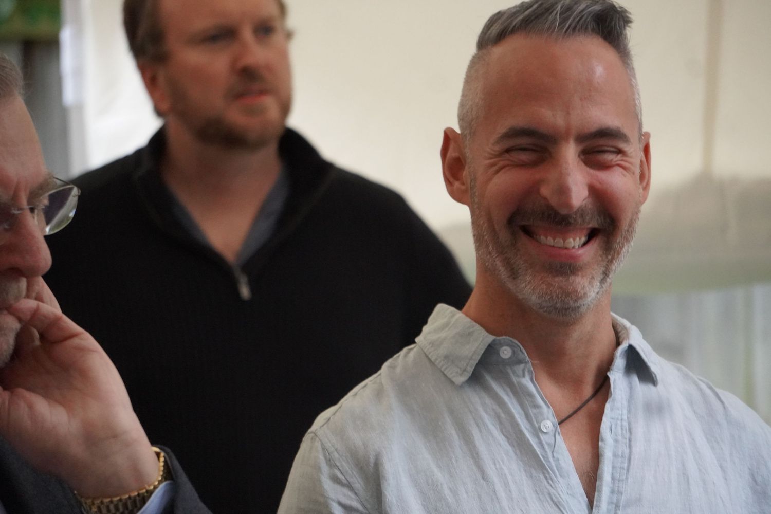 A man with salt and pepper hair and pale blue shirt smiles at the camera.