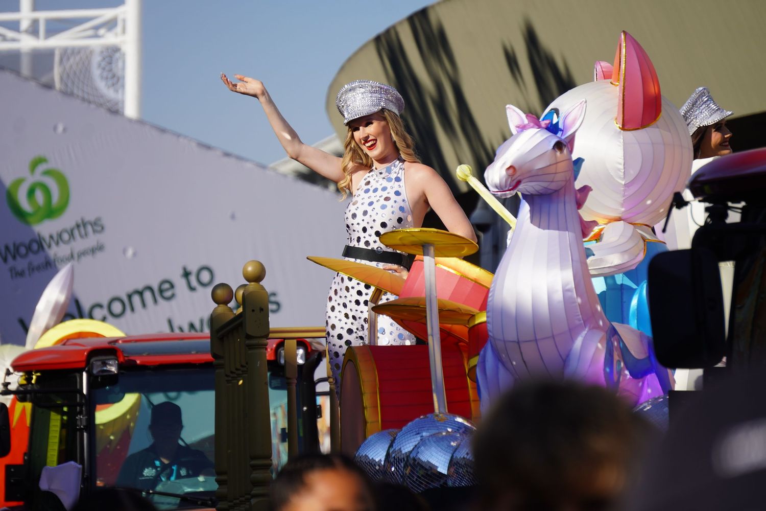 An entertainer at Sydney's Royal Easter Show is performing in a parade. She is wearing a white dress with black polka dots and is waving.