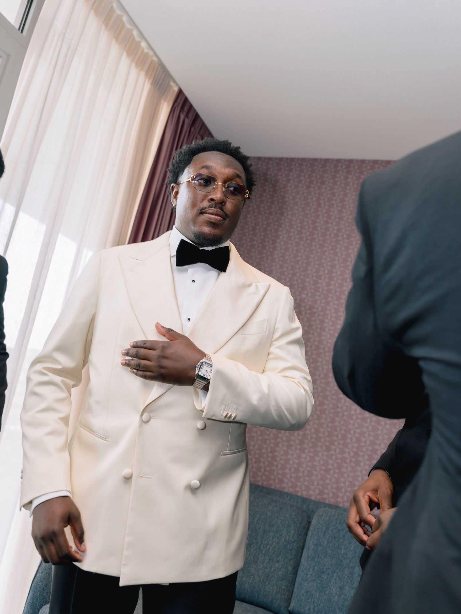 Groom in a stylish white tuxedo jacket looking over his shoulder while preparing for his wedding