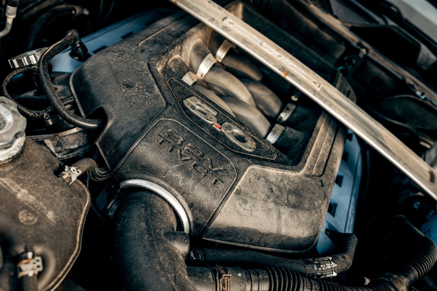 Close-up view of a car engine compartment showing various mechanical components and hoses.