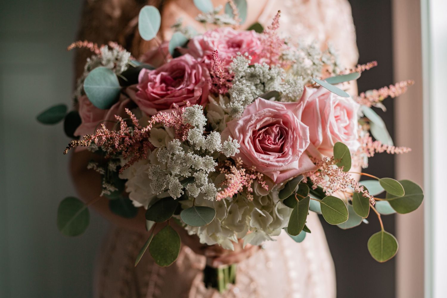 A collection of pink and white floral wedding bouquets with roses and greenery arranged in elegant displays.