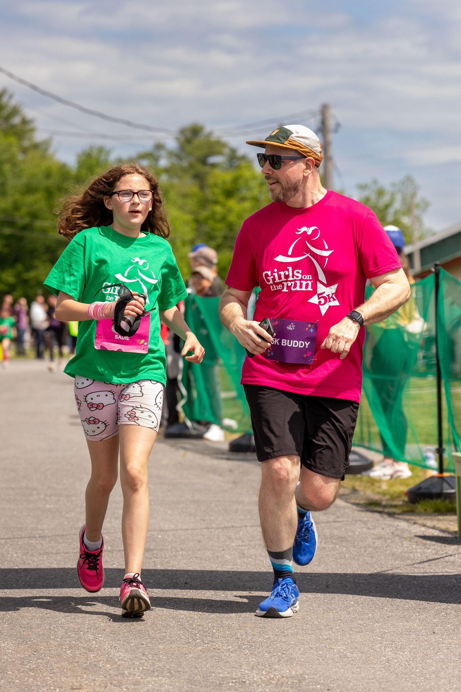 Adult buddy and young girl run together in Girls on the Run 5K charity race event.
