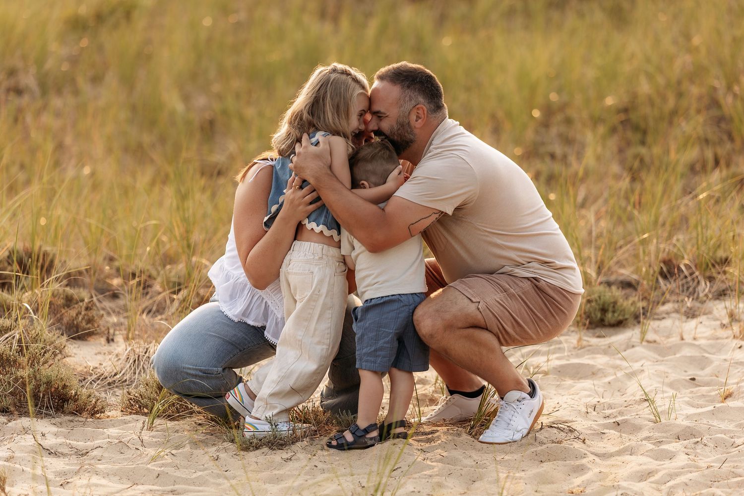 A couple embraces while sitting on a sandy beach path during golden hour.