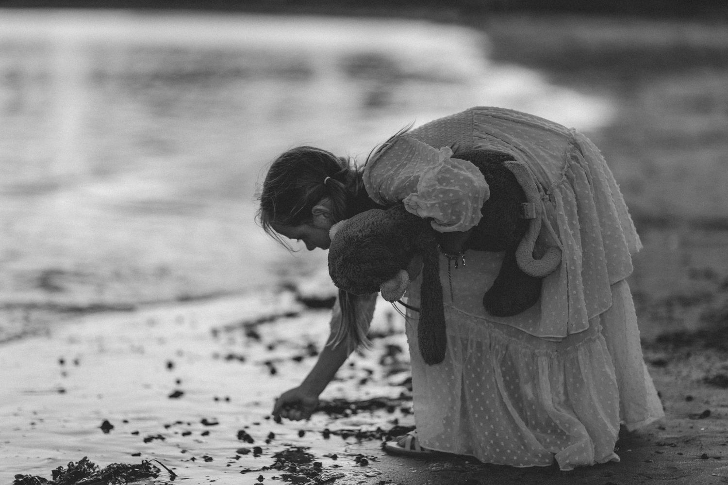 Black and white image of people exploring a rocky beach shoreline.