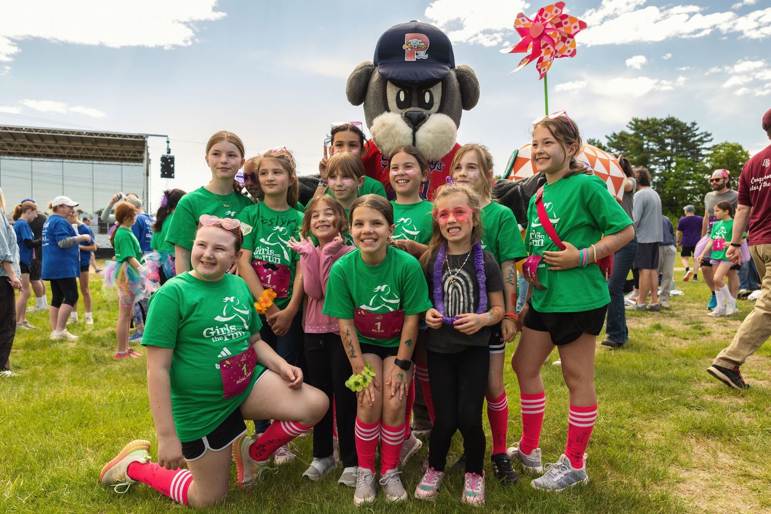 Group of girls posing with mascot costume at Girls on the Run outdoor event.