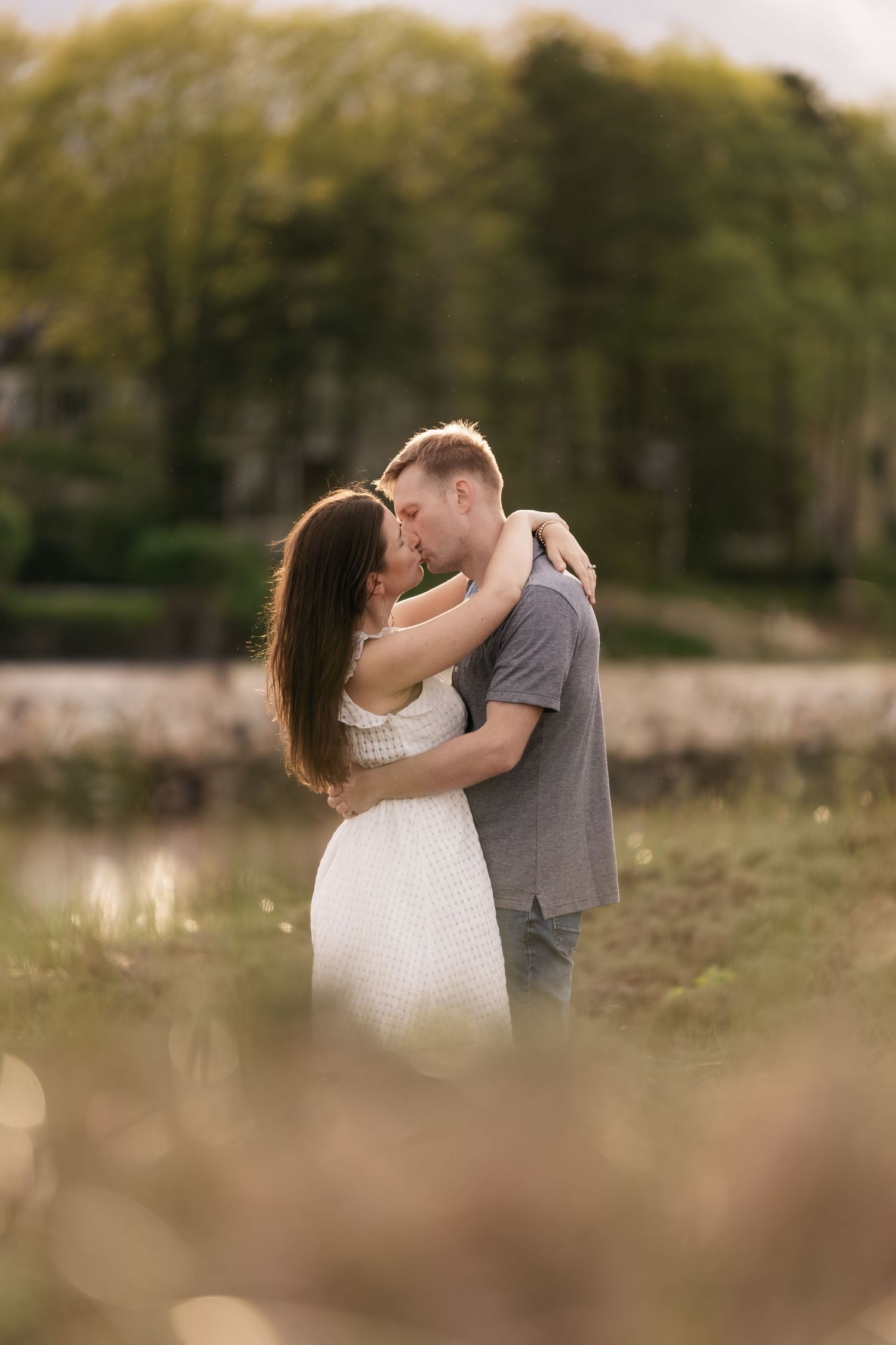 A romantic couple shares a tender kiss in a natural outdoor setting.